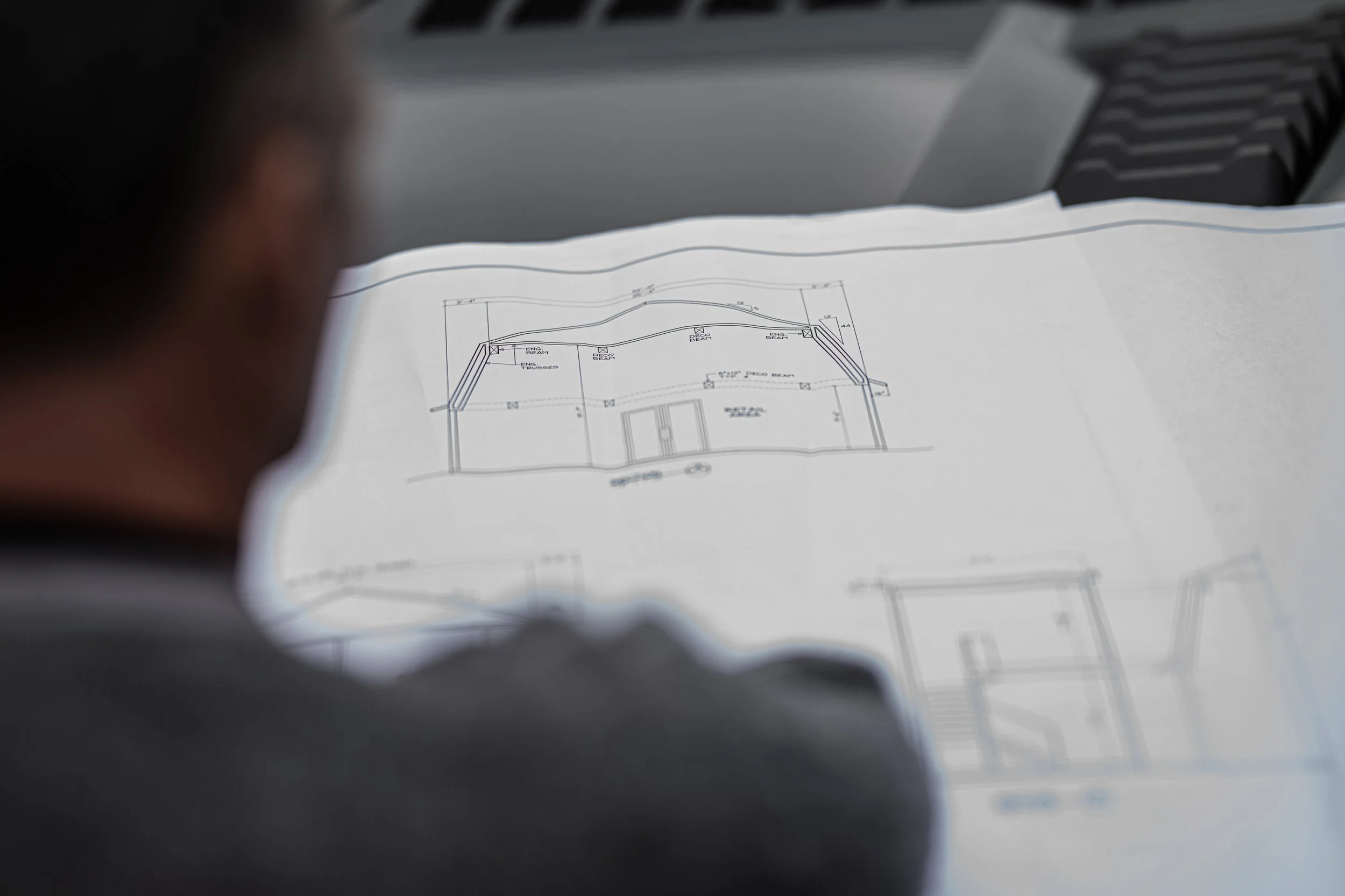 Person viewing an architectural blueprint with building sketches and measurements.