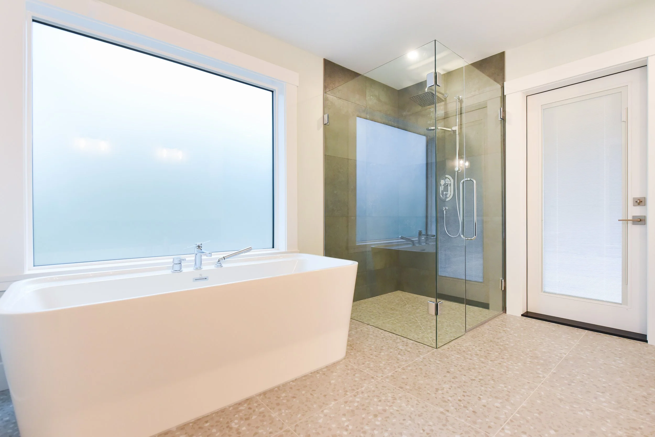 Modern bathroom with large frosted window, white bathtub, and glass shower enclosure with rain shower and handheld showerhead.
