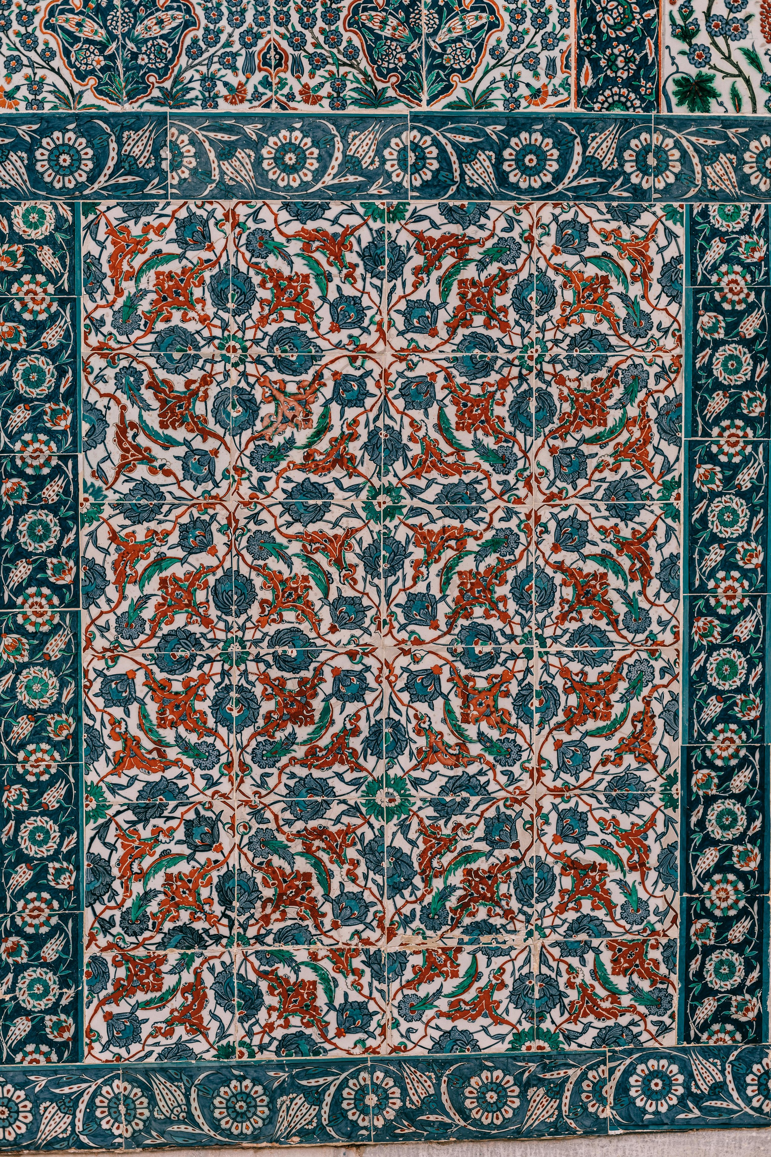 Close-up of a decorative tiled wall featuring intricate floral and geometric patterns in blue, teal, and orange colors.