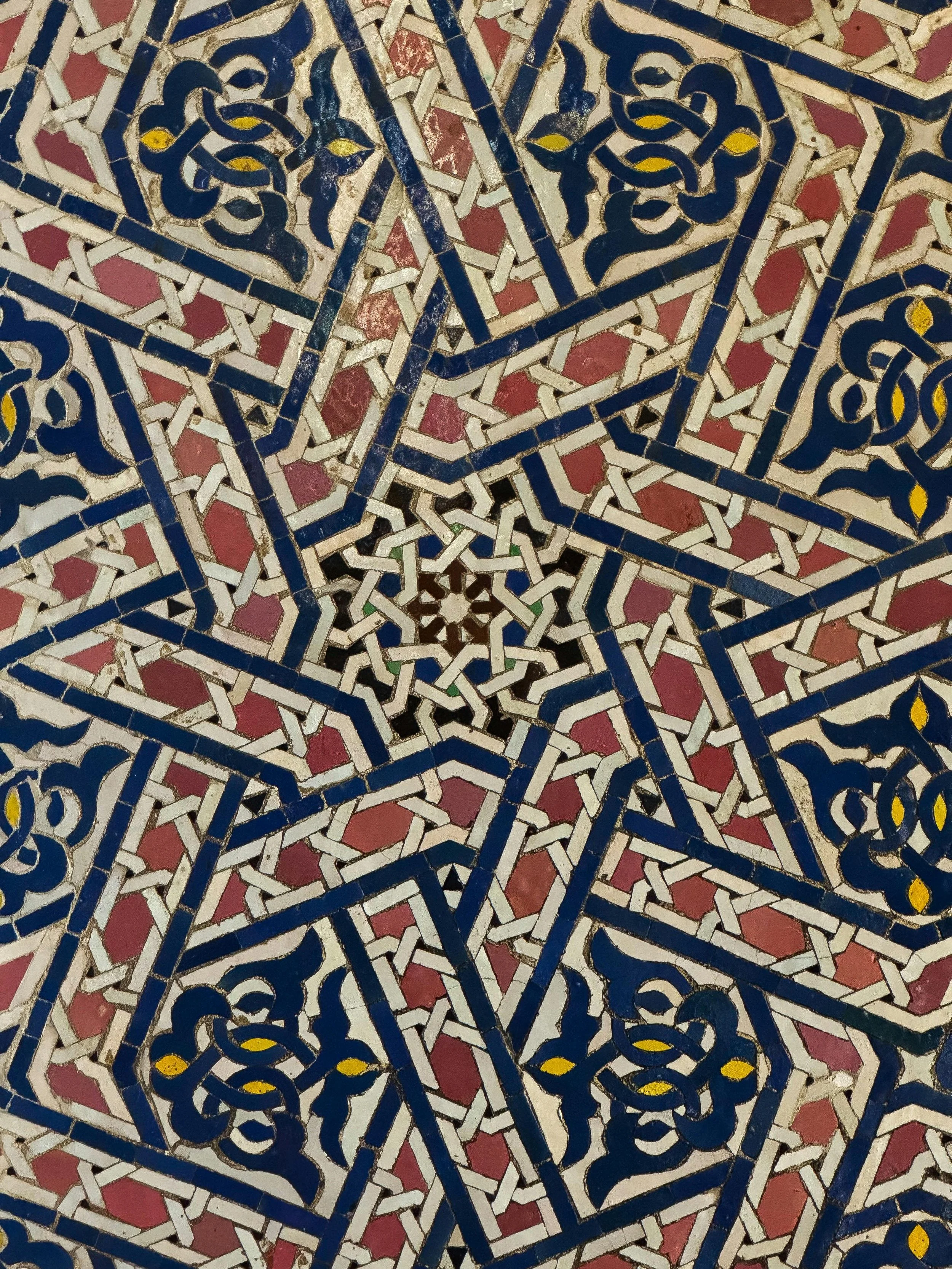 Close-up of intricate Moroccan tiled mosaic with geometric patterns in blue, white, pink, and yellow accents.