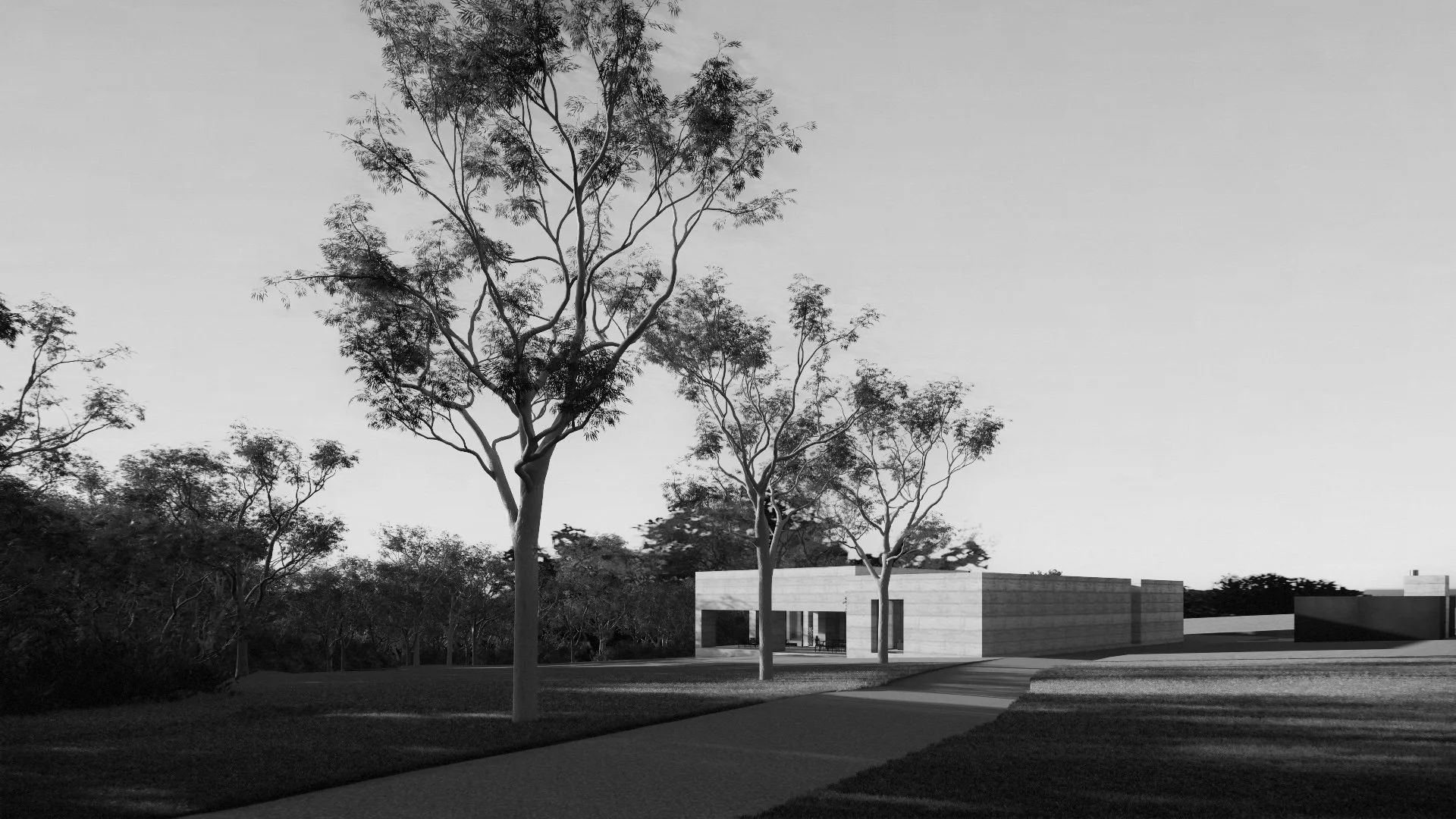 Modern building with large windows surrounded by trees and a path in a park-like setting during the daytime.
