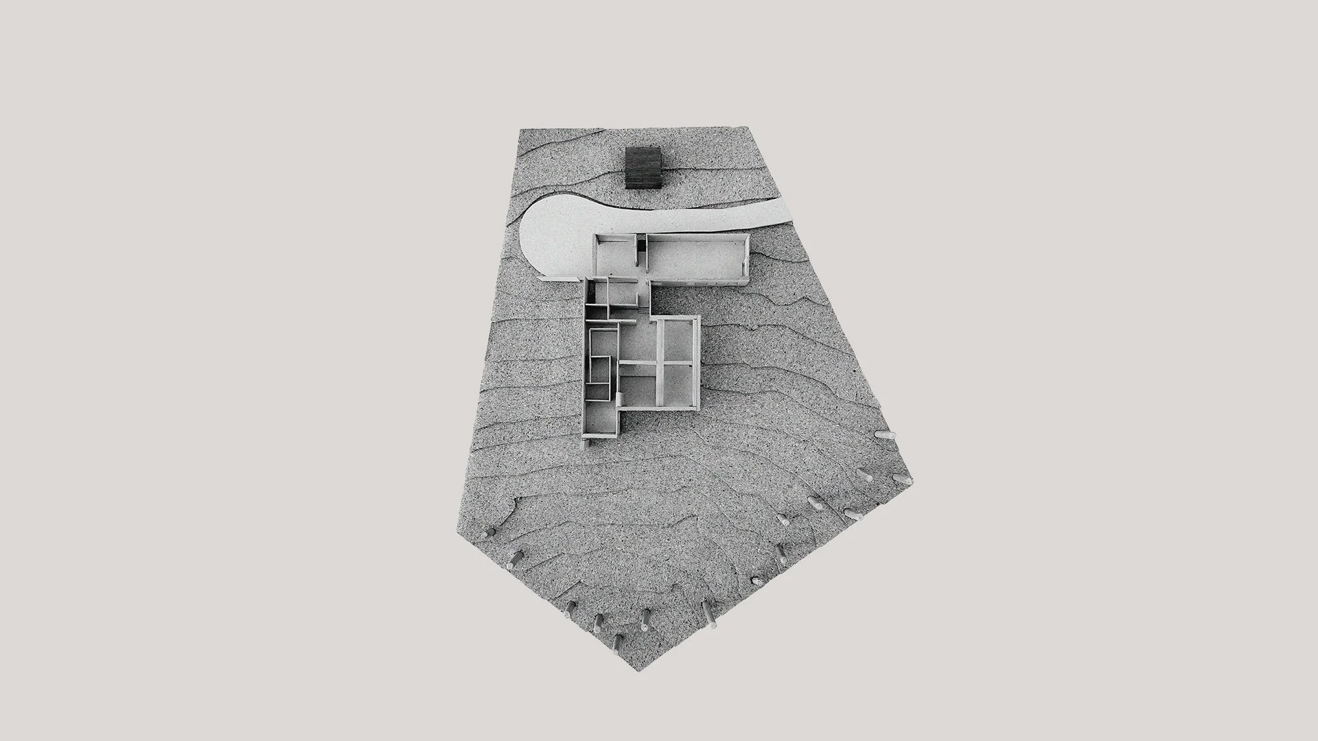 Architectural model showing building layout on a textured, curvy gray base with a curved white pathway and black rectangular element.