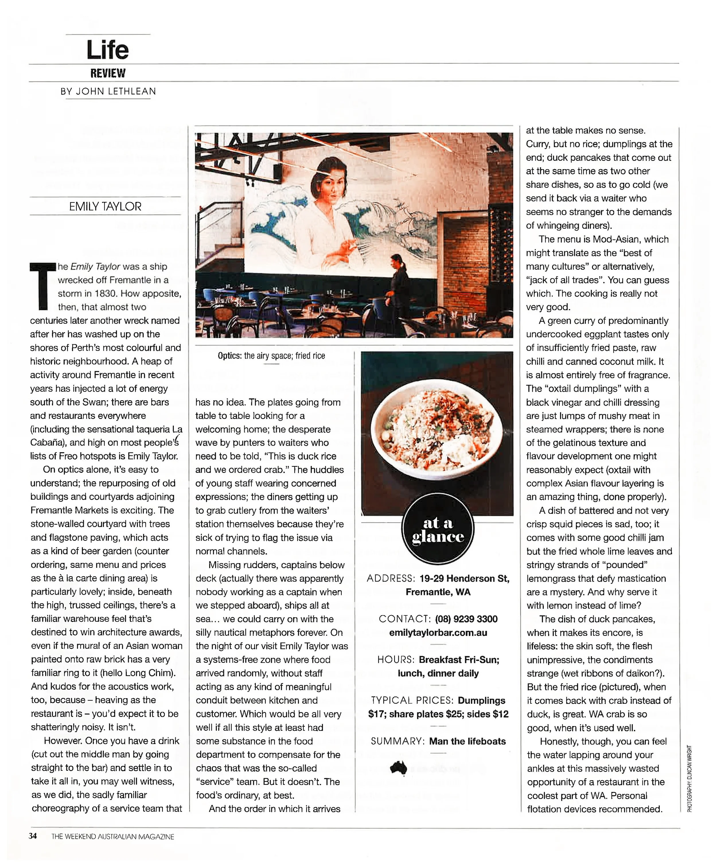 A magazine page featuring a review of a restaurant called 'at a glance'. The page contains a large photo of a woman in a white shirt standing inside the restaurant with a mural of Mount Fuji and clouds on the wall behind her. There is also an image of a bowl of duck rice and the restaurant's address, contact info, hours, and prices listed on the page.