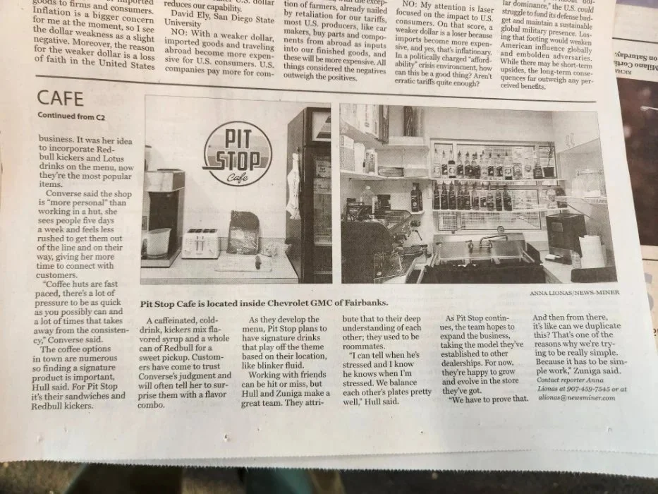 Interior of Pit Stop Cafe inside Chevrolet GMC of Fairbanks, showing service counter, drink syrups, espresso equipment, and Pit Stop Cafe logo on the wall.