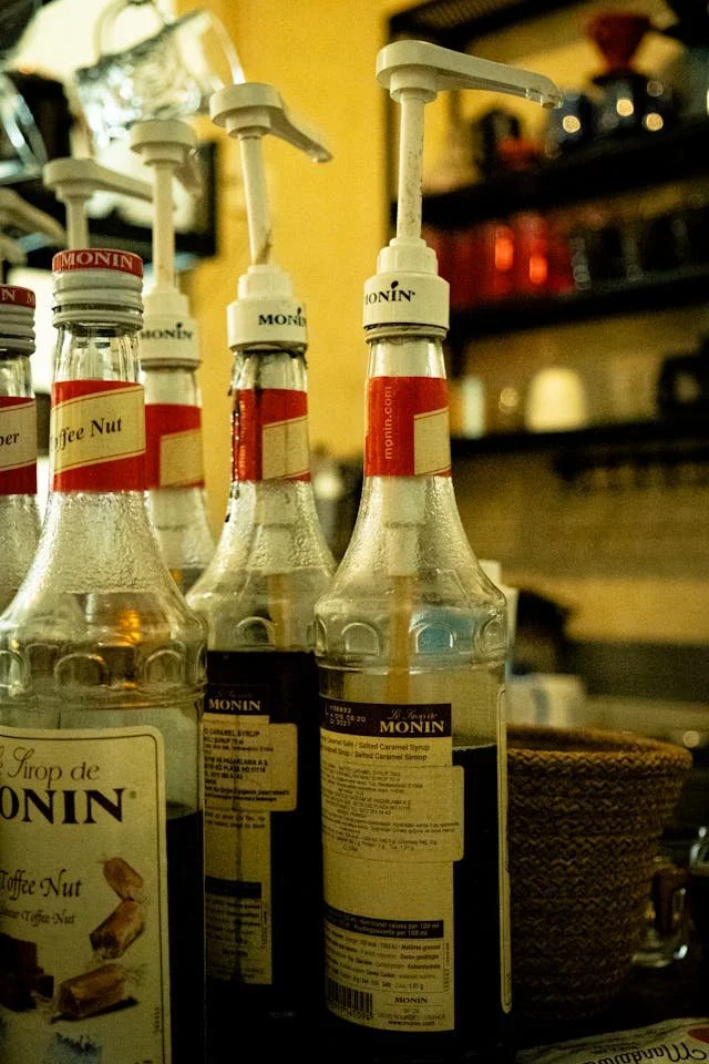 Monin flavored syrup bottles with pump dispensers behind the counter at Pit Stop Cafe, used to craft custom coffee and energy drinks