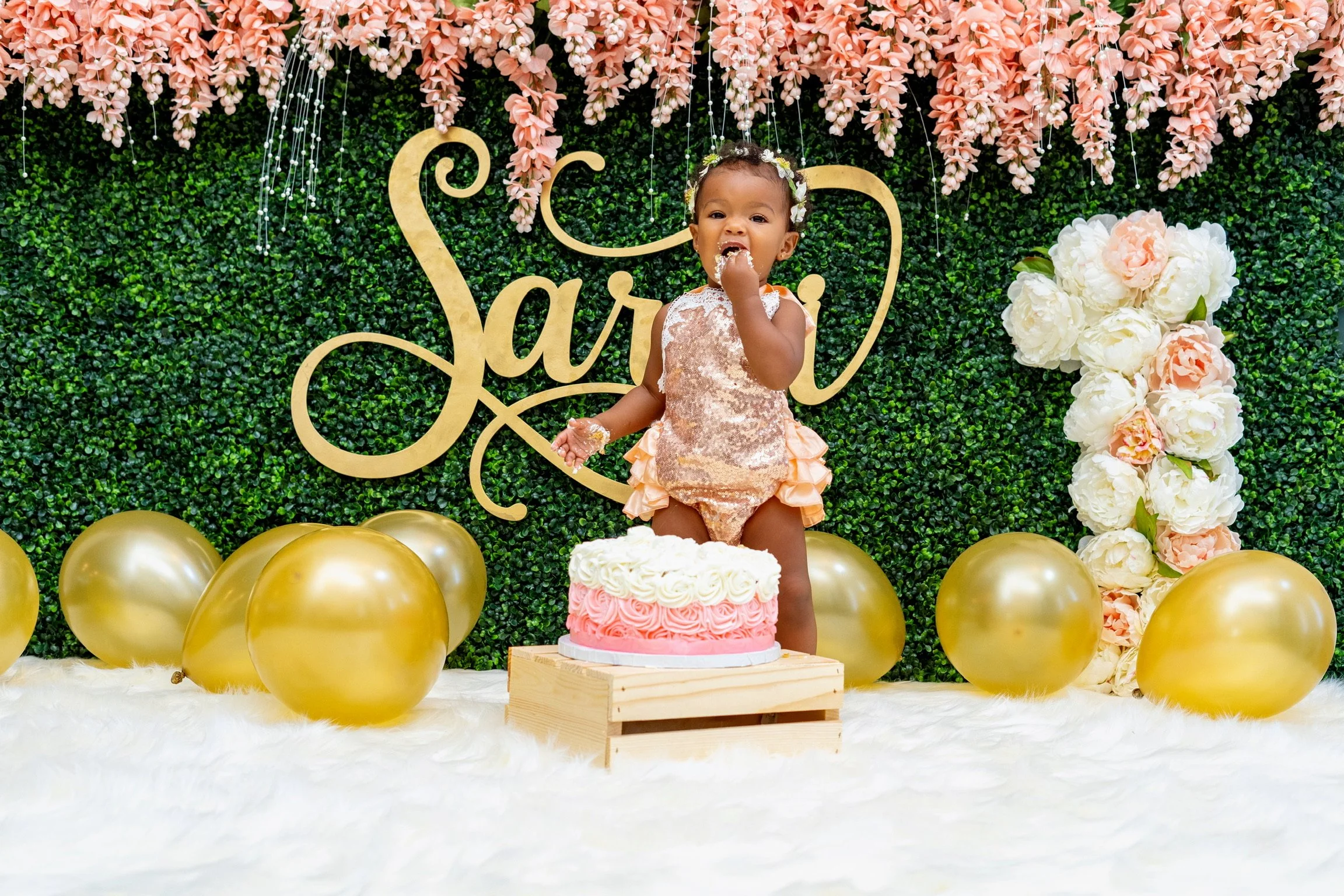 A smiling couple holding hands outdoors near a lake with colorful fall trees in the background.