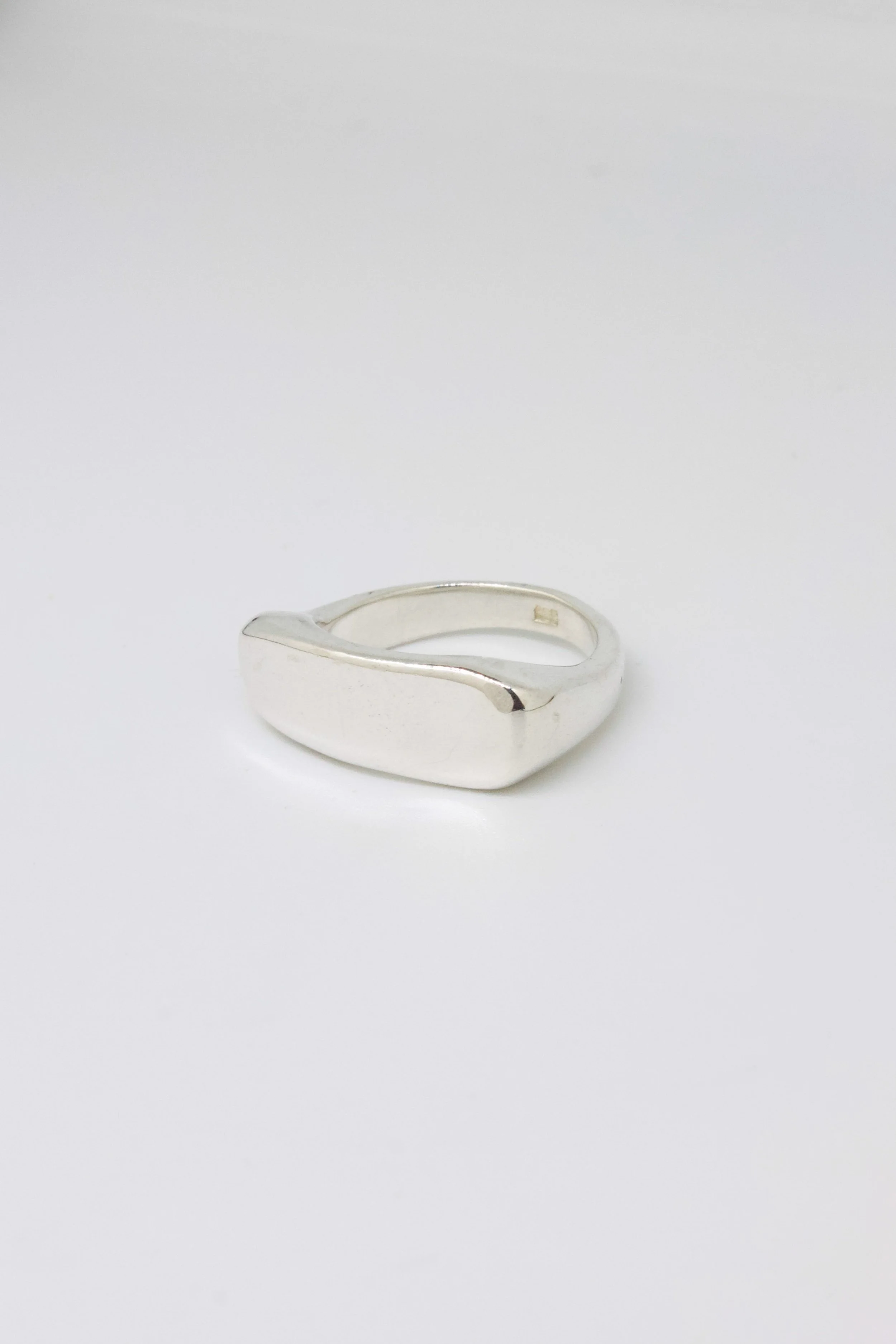 A silver ring with a smooth, rounded surface, placed on a plain white background.