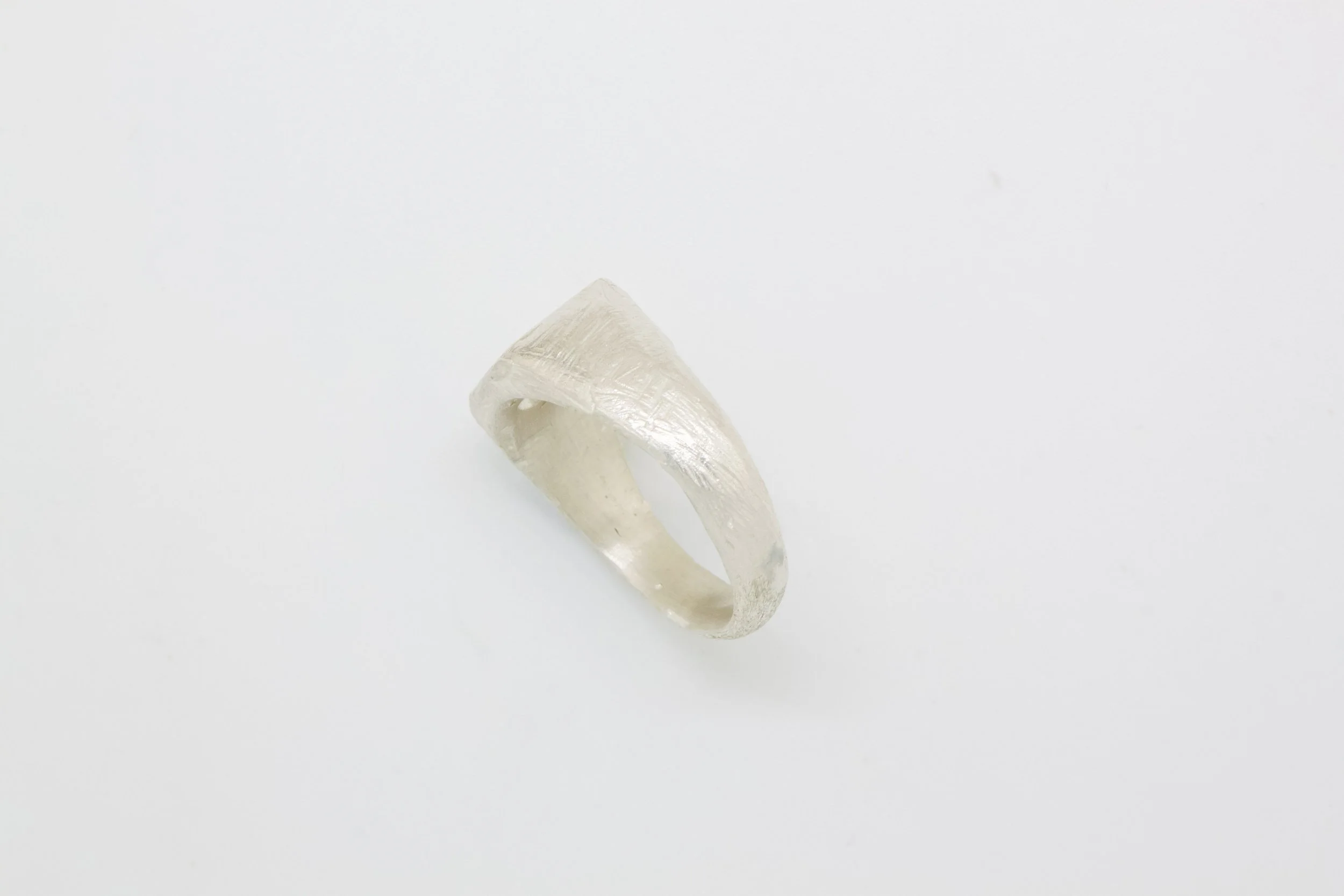 Silver ring with a textured, geometric design on a plain white background.