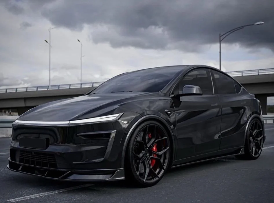 Black modern sports coupe car parked on an empty road under cloudy sky.