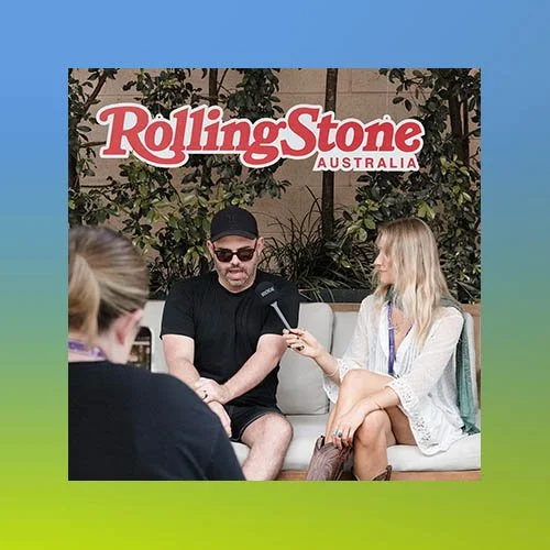 Person being interviewed at a Rolling Stone Australia event, seated on a sofa outdoors with greenery and a Rolling Stone Australia sign in the background.