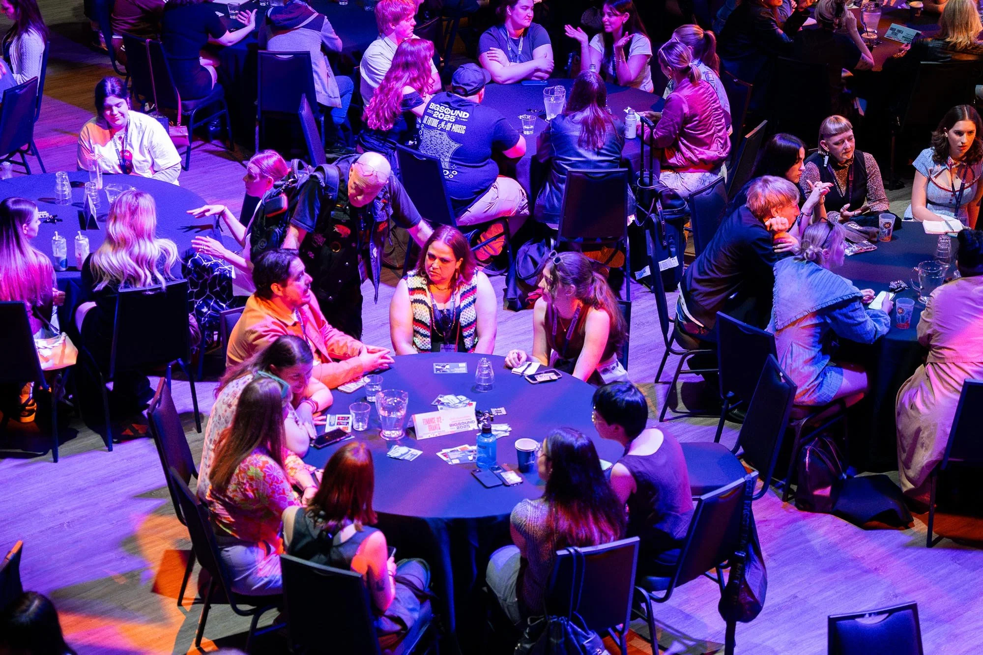 People sitting around tables playing cards at an event.