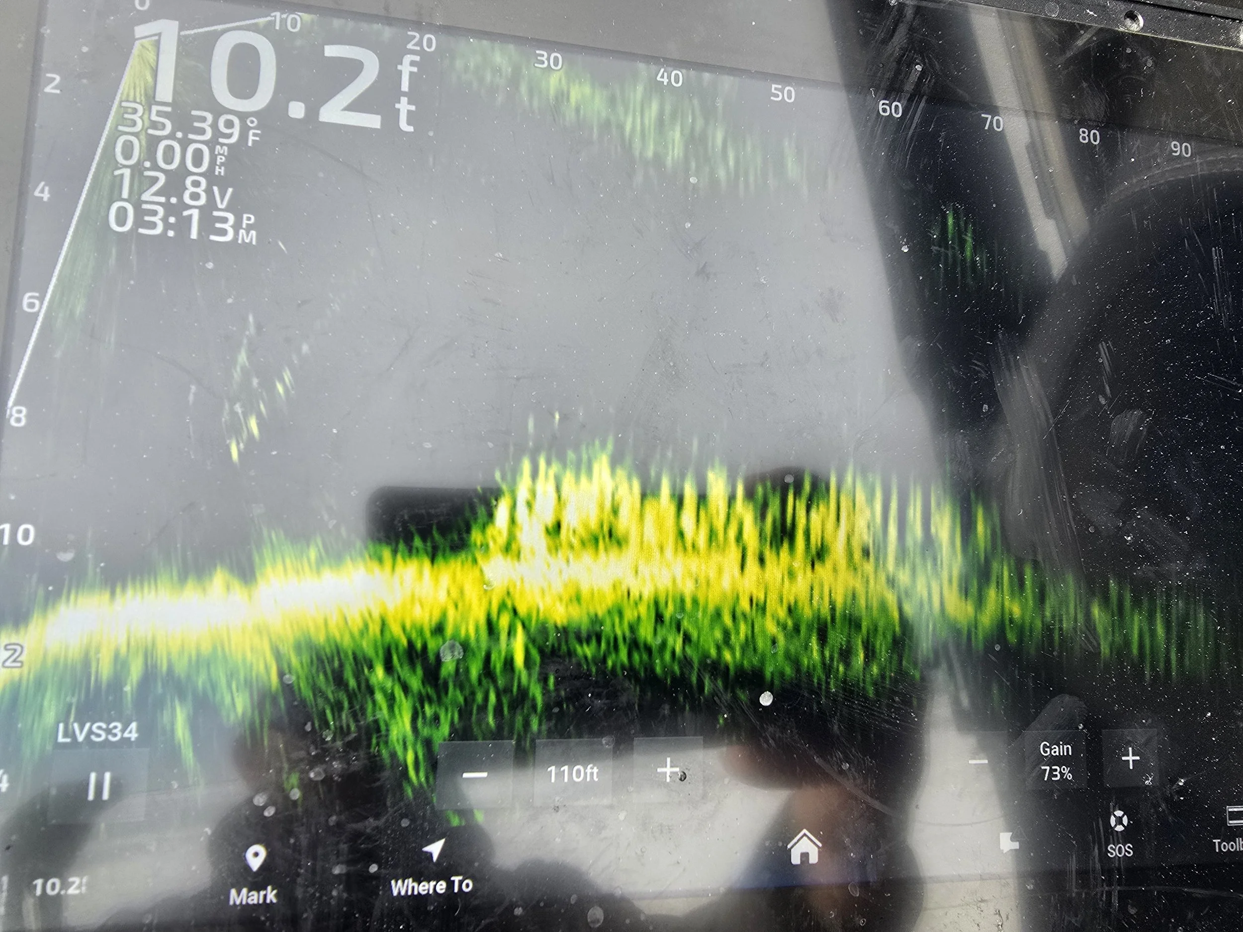 A digital display showing various data including a depth of 0.2 feet, temperature of 35.39°F, and other electronic measurement readings, overlaid with a colorful sonar or fishfinder visualization.