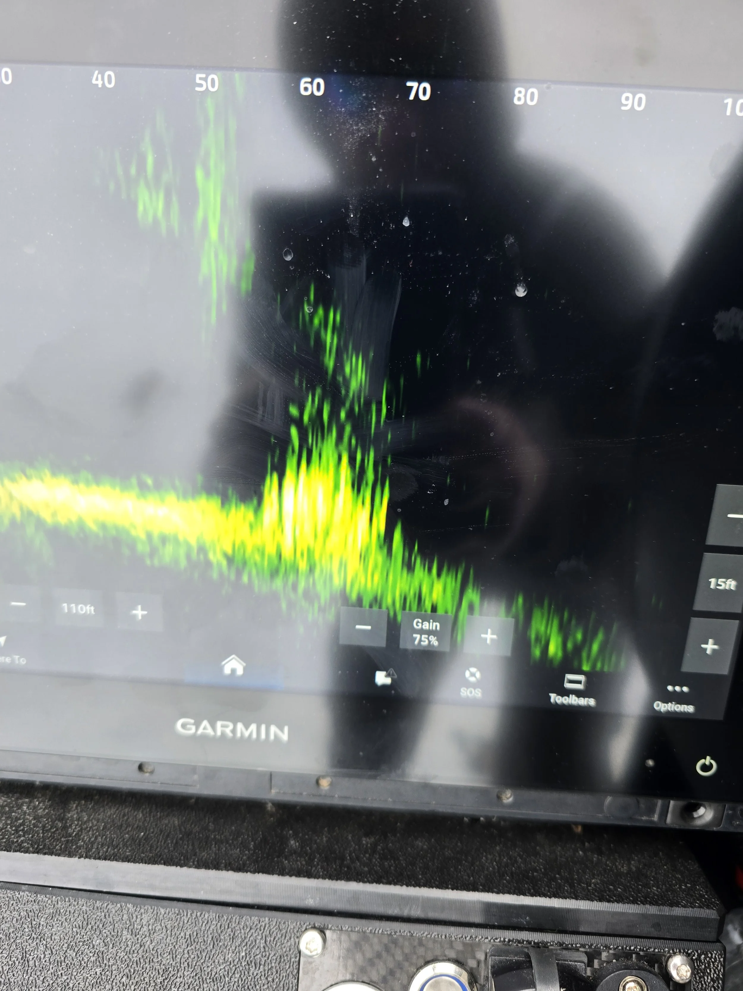 Garmin marine GPS device screen showing depth data with a green wave pattern, gain set to 75%, and various control icons below.