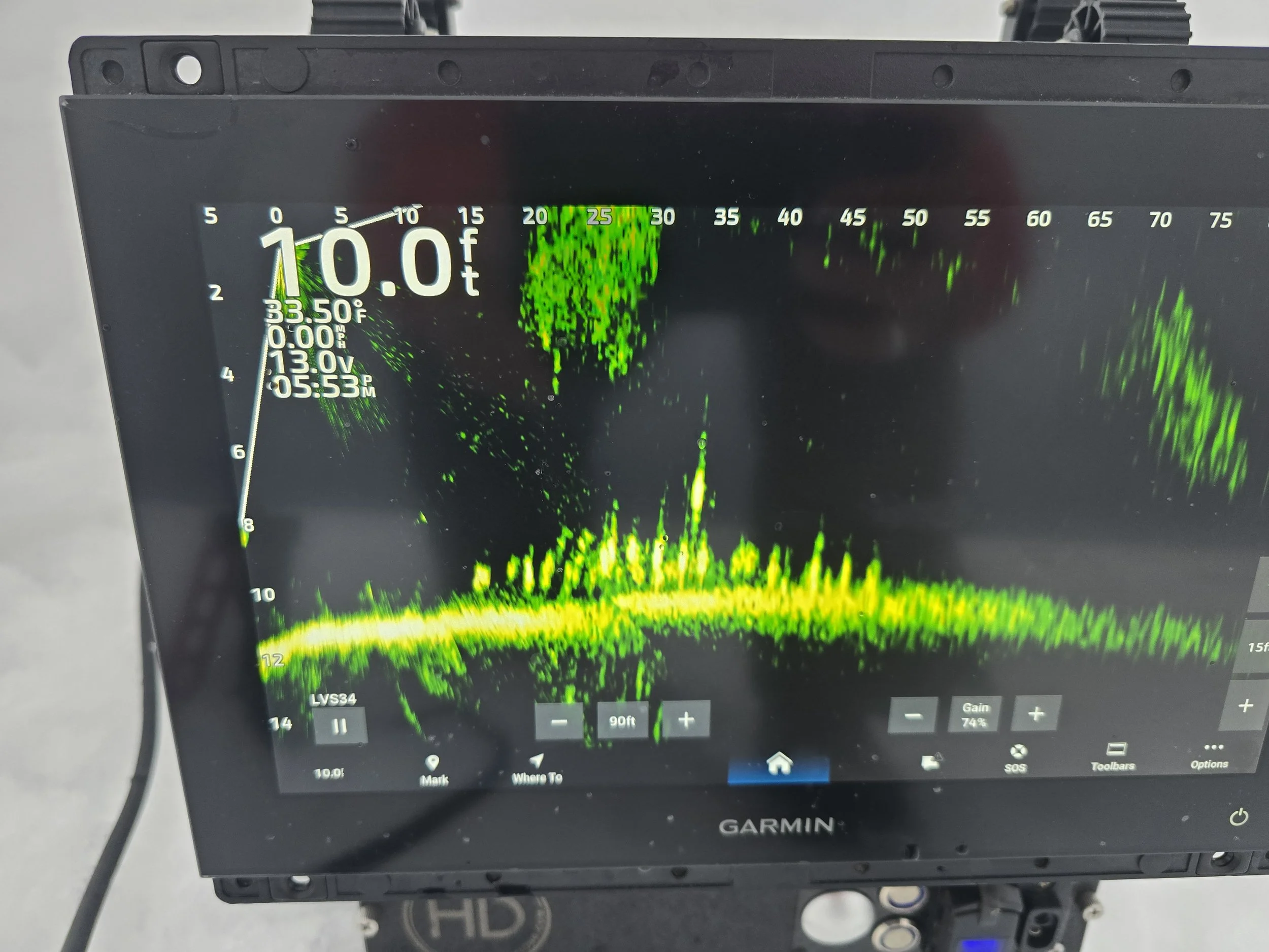 A Garmin fish finder display showing a depth of 10.0 feet, water temperature of 33.5°F, and a sonar image with green and yellow markings indicating underwater structures or fish.