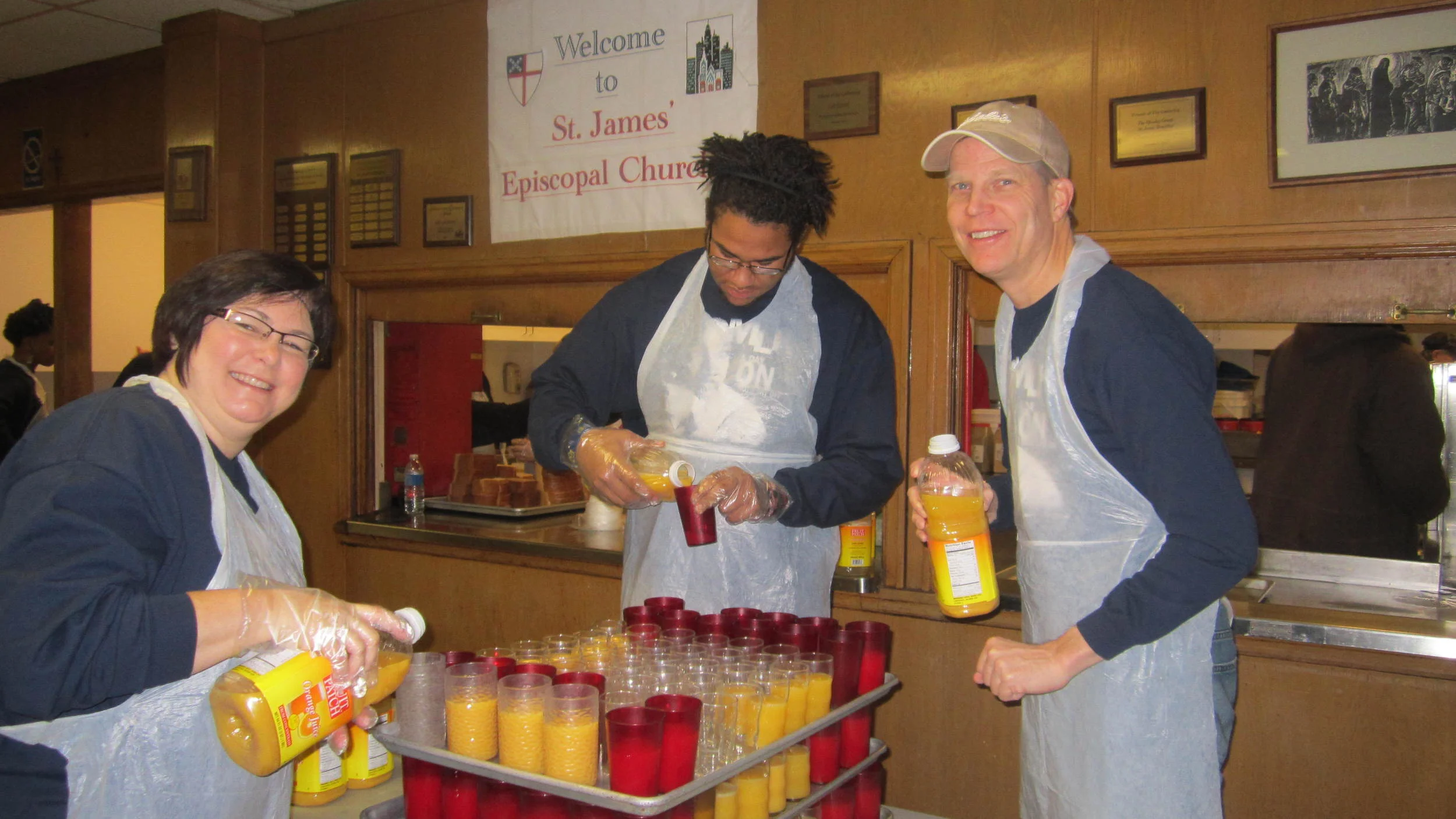 Volunteers fill up orange juice for breakfast at St. James