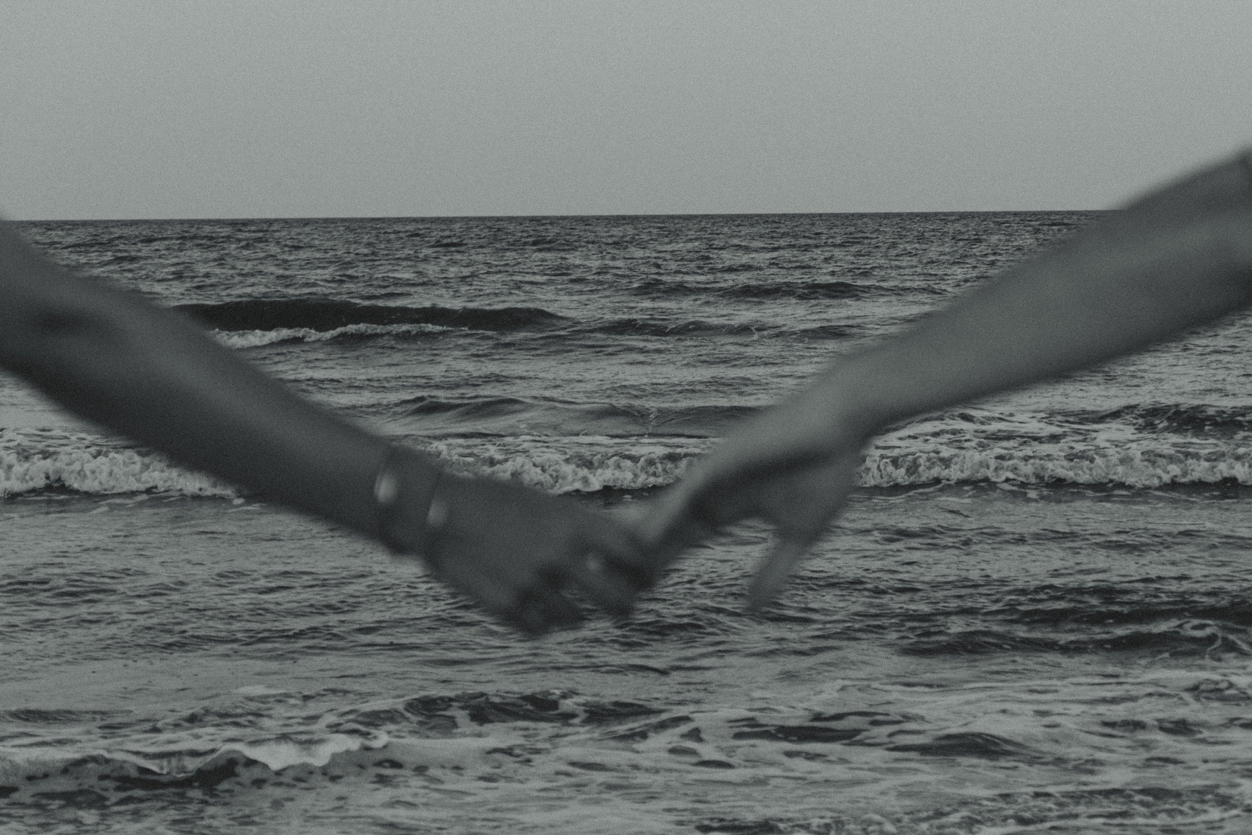 View of the ocean with small waves, framed by blurred out metal pipes in the foreground.