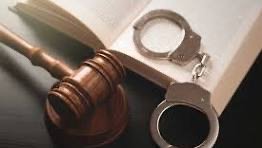 A gavel and a pair of handcuffs on a table.