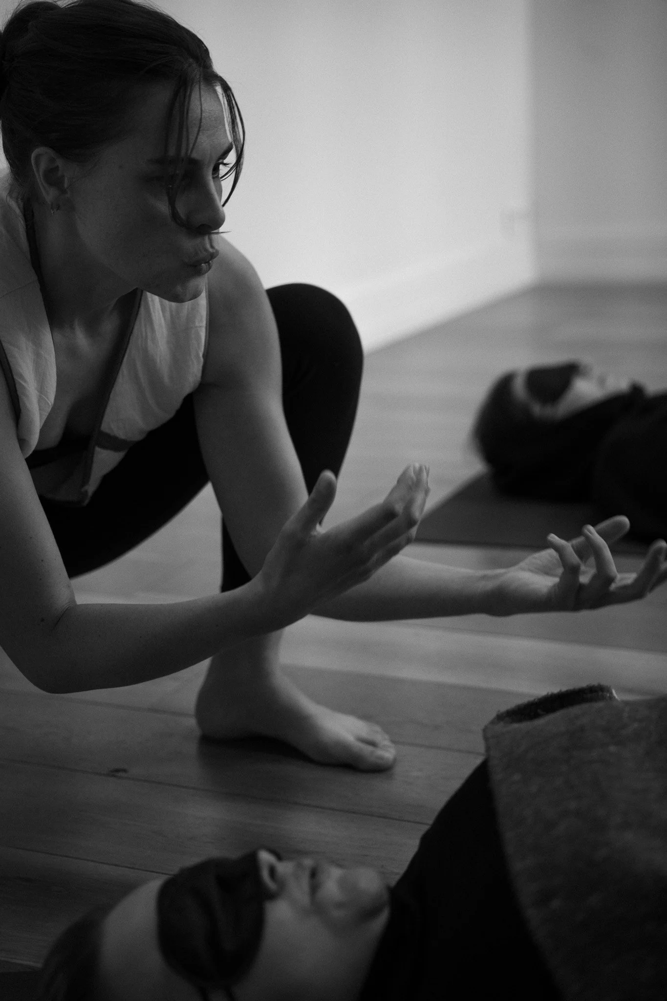 Une femme en position de yoga, faisant un mouvement énergétique pour accompagner quelqu'un à libérer en pleine séance de breathwork.
