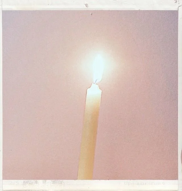 Une bougie allumée sur un fond rose