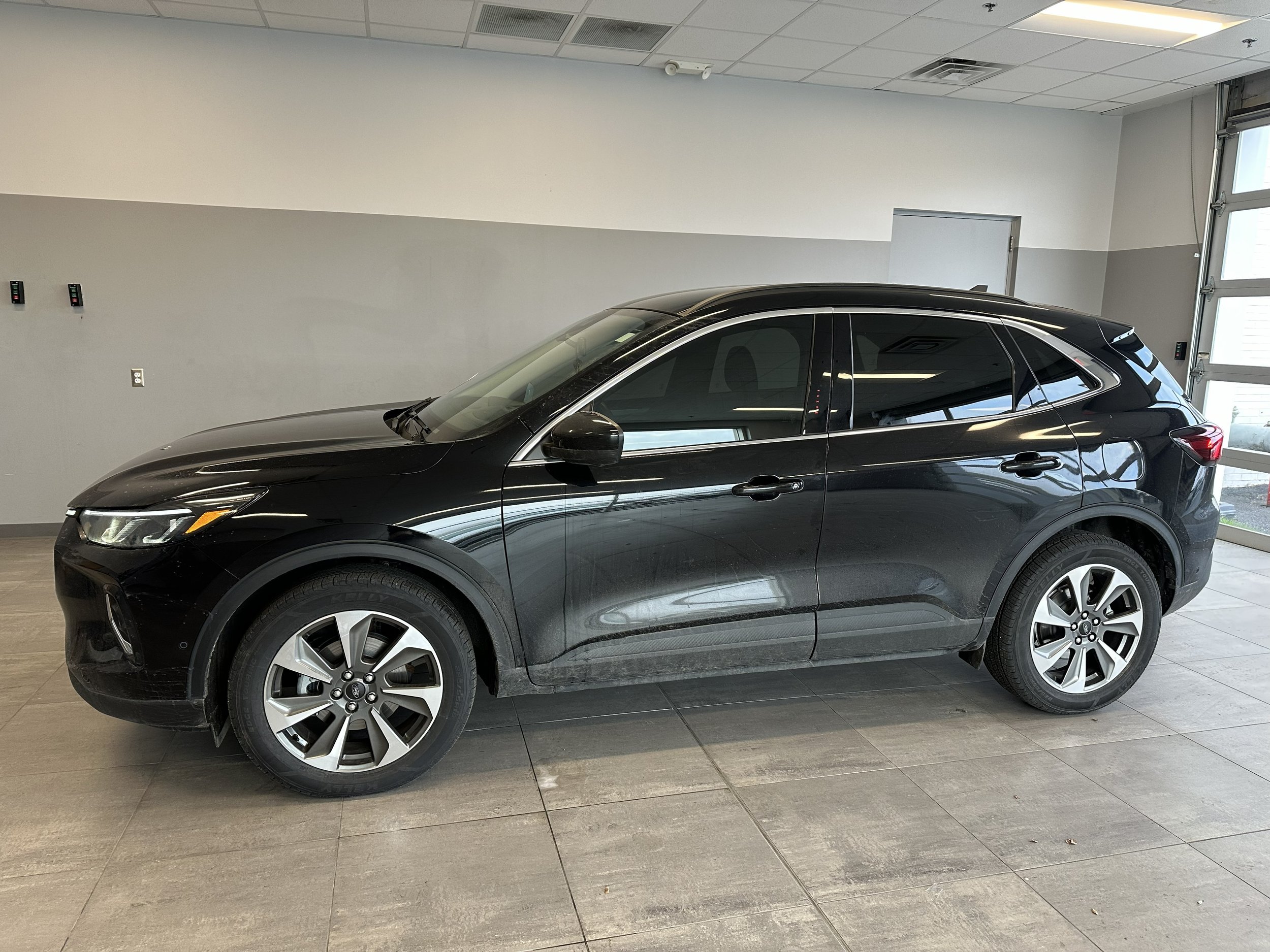 A Tinted Black SUV parked indoors in a showroom with gray walls and a tiled floor.