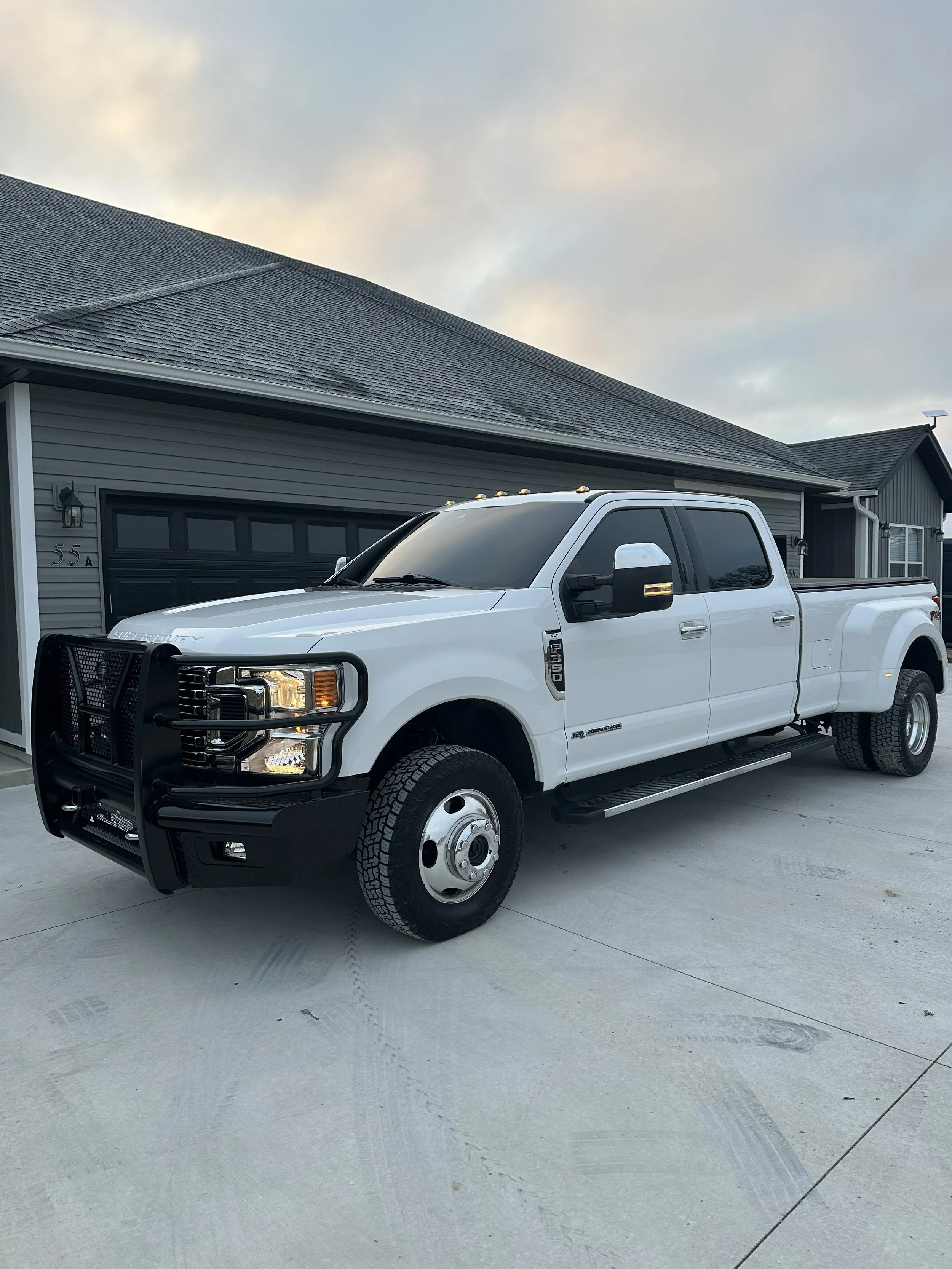 White Ford F-450 Super Duty pickup truck parked in driveway with tinted windows.