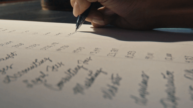 Close-up of a person's hand writing on a paper with a pen.