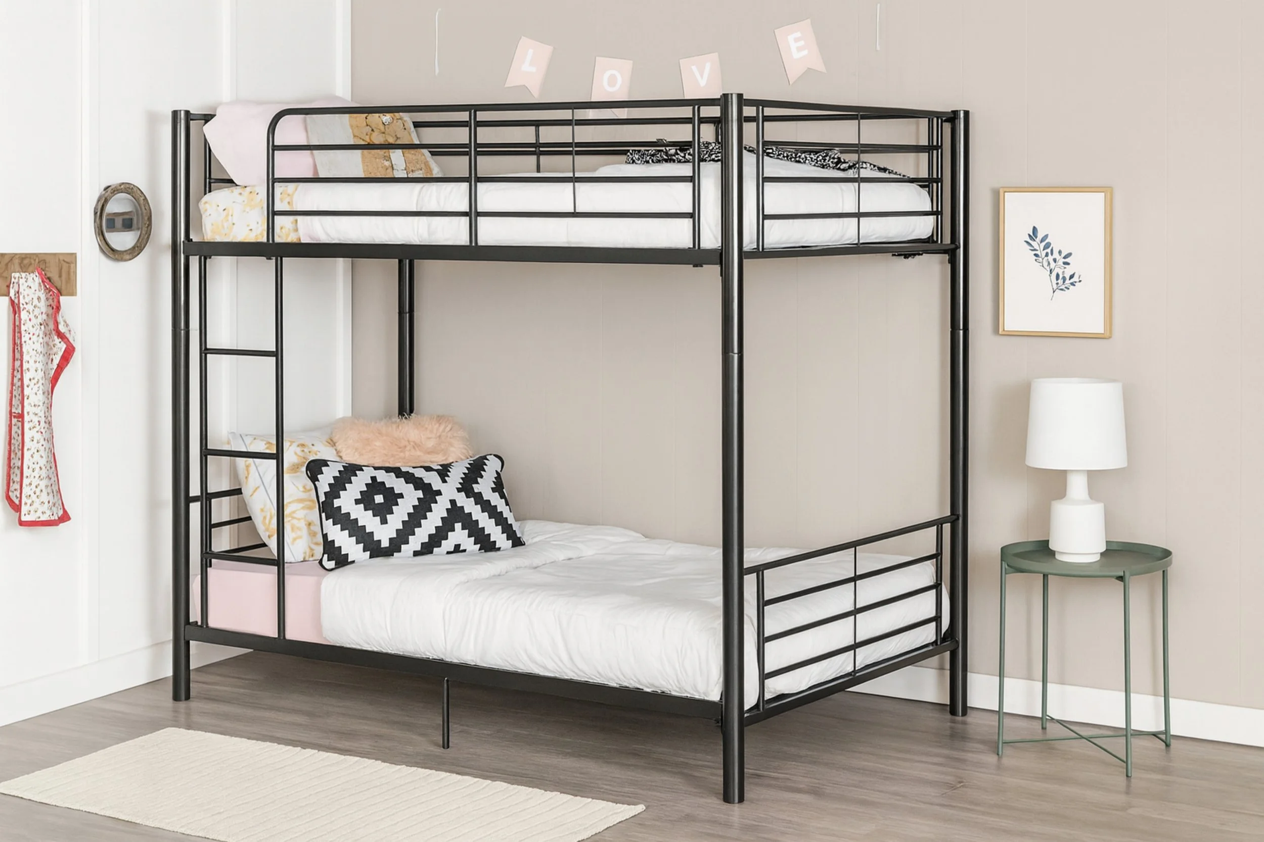 Lits superposés dans une chambre, décor moderne avec un tableau de feuilles, une lampe blanche et une bannière avec le mot LOVE.