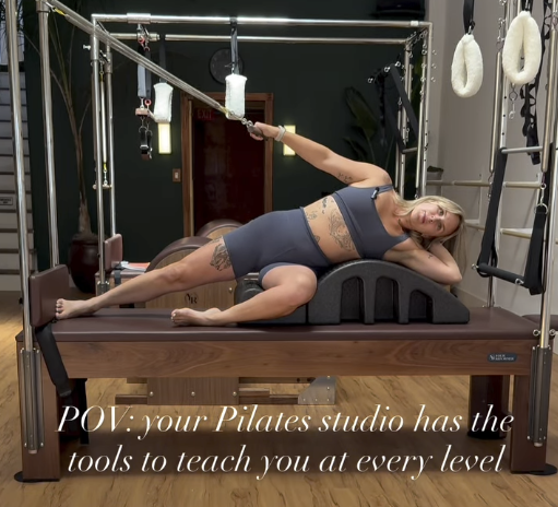 an image of a woman doing Pilates on the Cadillac Machine with the overlay: POV: your pilates studio has the tools to teach you at every level