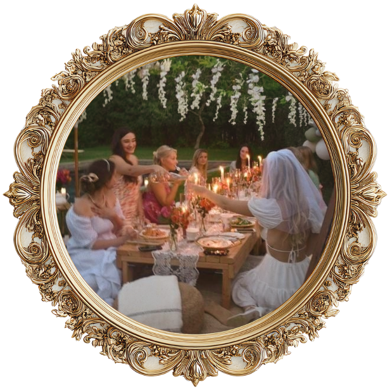 A group of women celebrating at an outdoor dinner party, with a beautifully decorated table and hanging white flowers overhead.