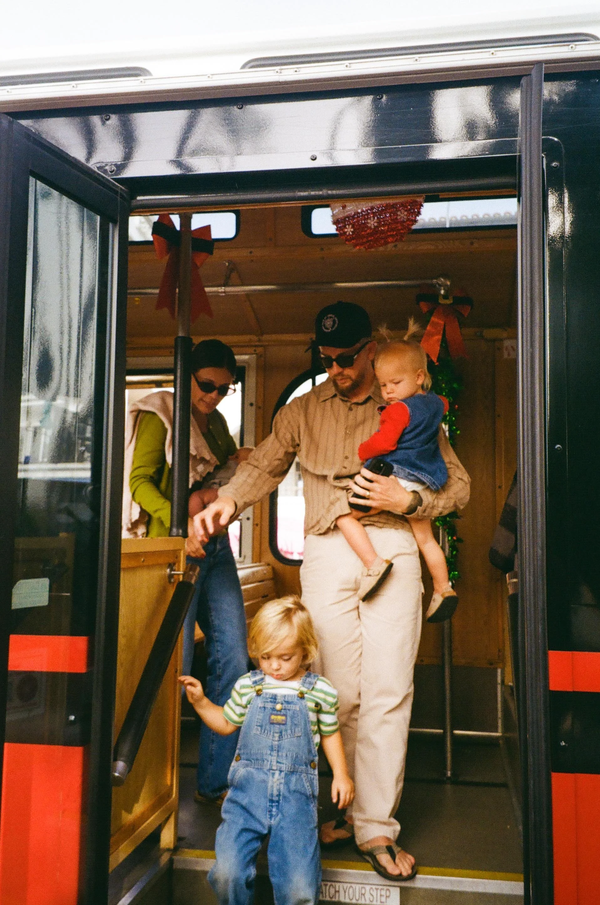 A family with young children at the entrance of a bus decorated for Christmas, with Christmas ornaments and bows inside. in San Clemente California