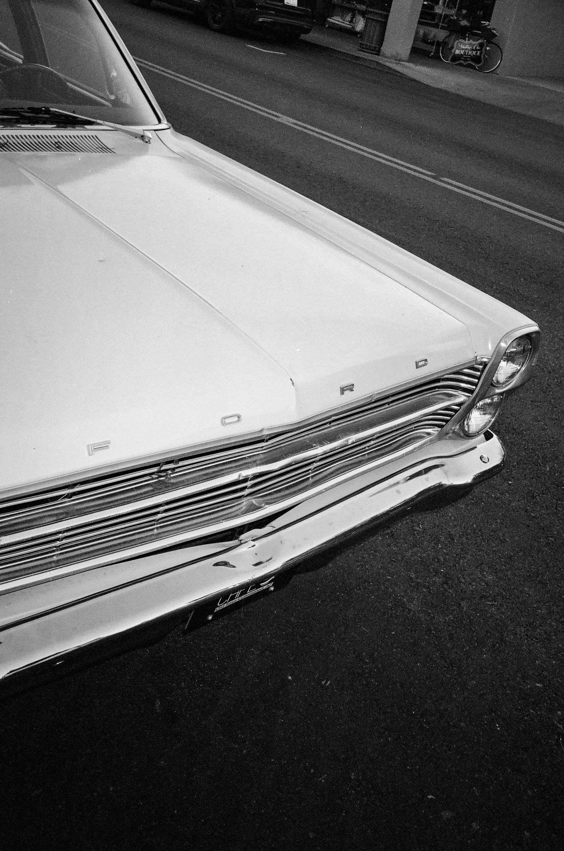 Close-up of the front of a vintage Ford car parked on the street, black and white photo.