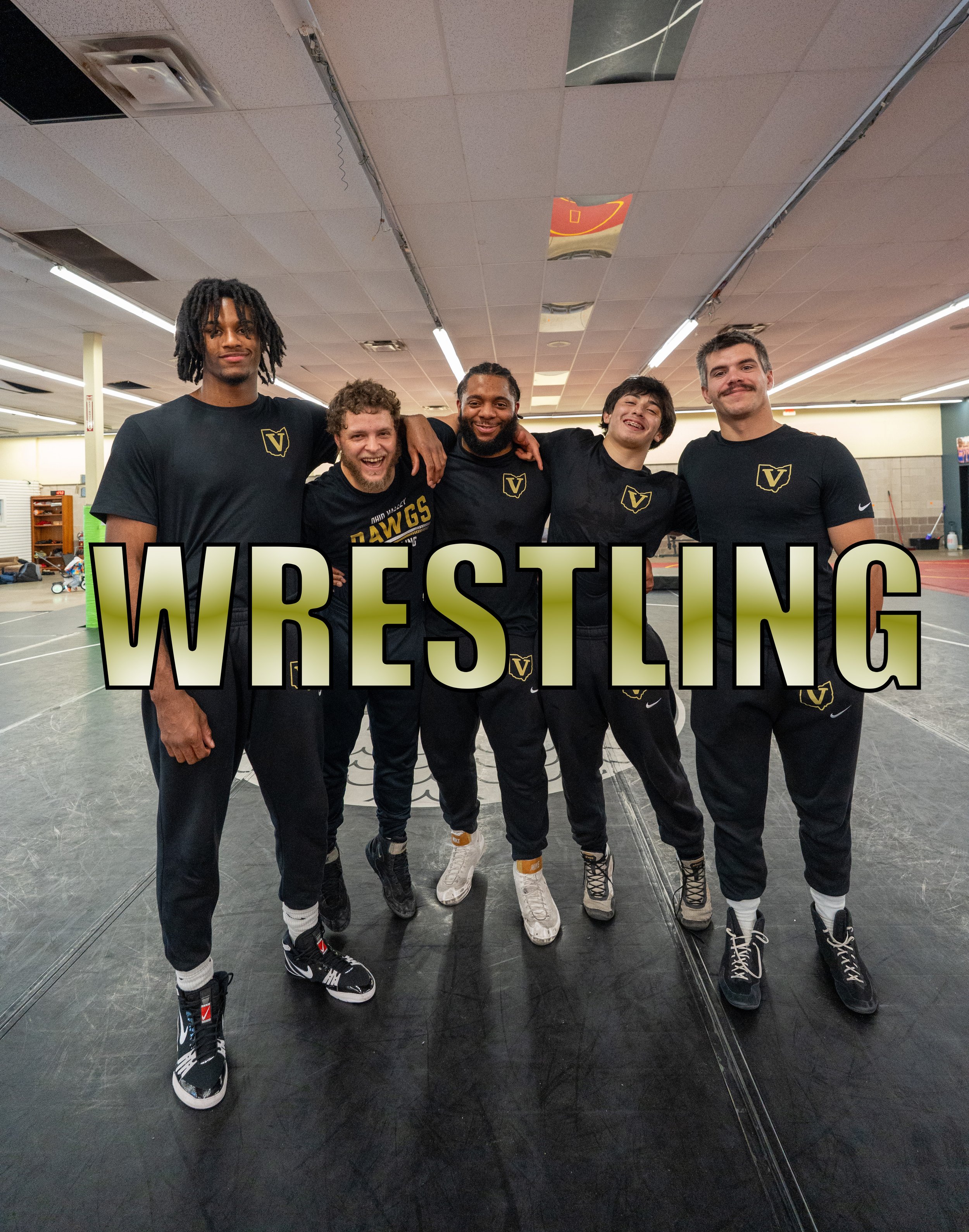 Five wrestlers standing together in a gym, smiling, wearing black athletic clothing with a crest logo, with the word 'WRESTLING' in large text overlay.