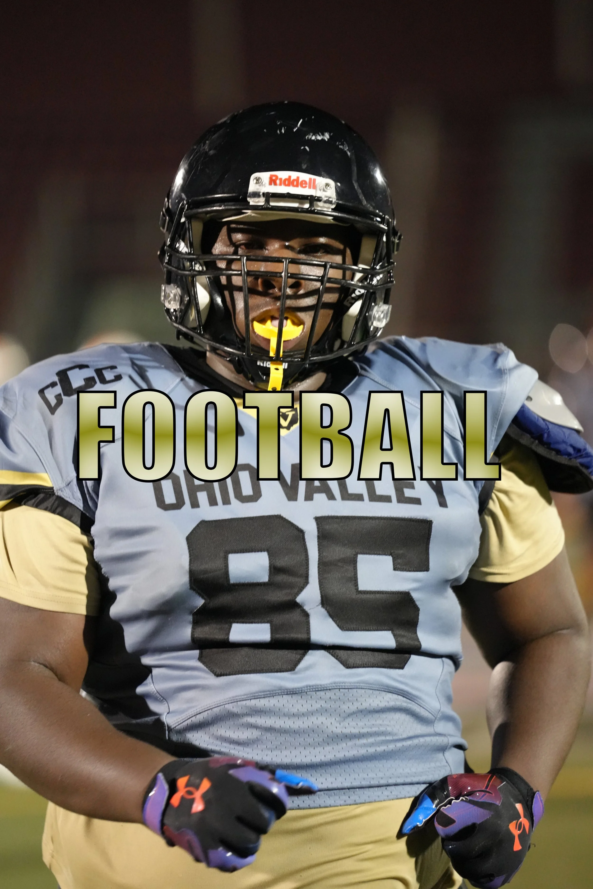 An American football player in a gray and yellow uniform with the number 85, wearing a black helmet and gloves, standing on the field during night time. The word 'FOOTBALL' is overlaid on the image.