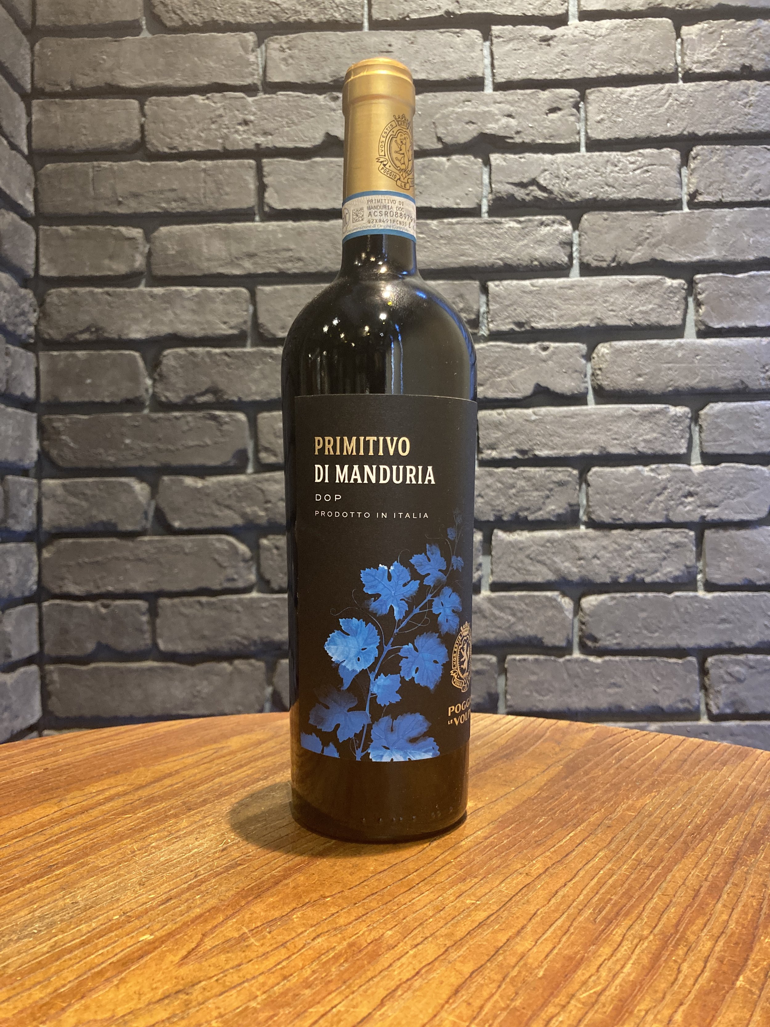 黒いラベルのイタリア産ワインボトル。ラベルには青い植物のイラストと「PRIMITIVO DI MANDURIA」と書かれている。