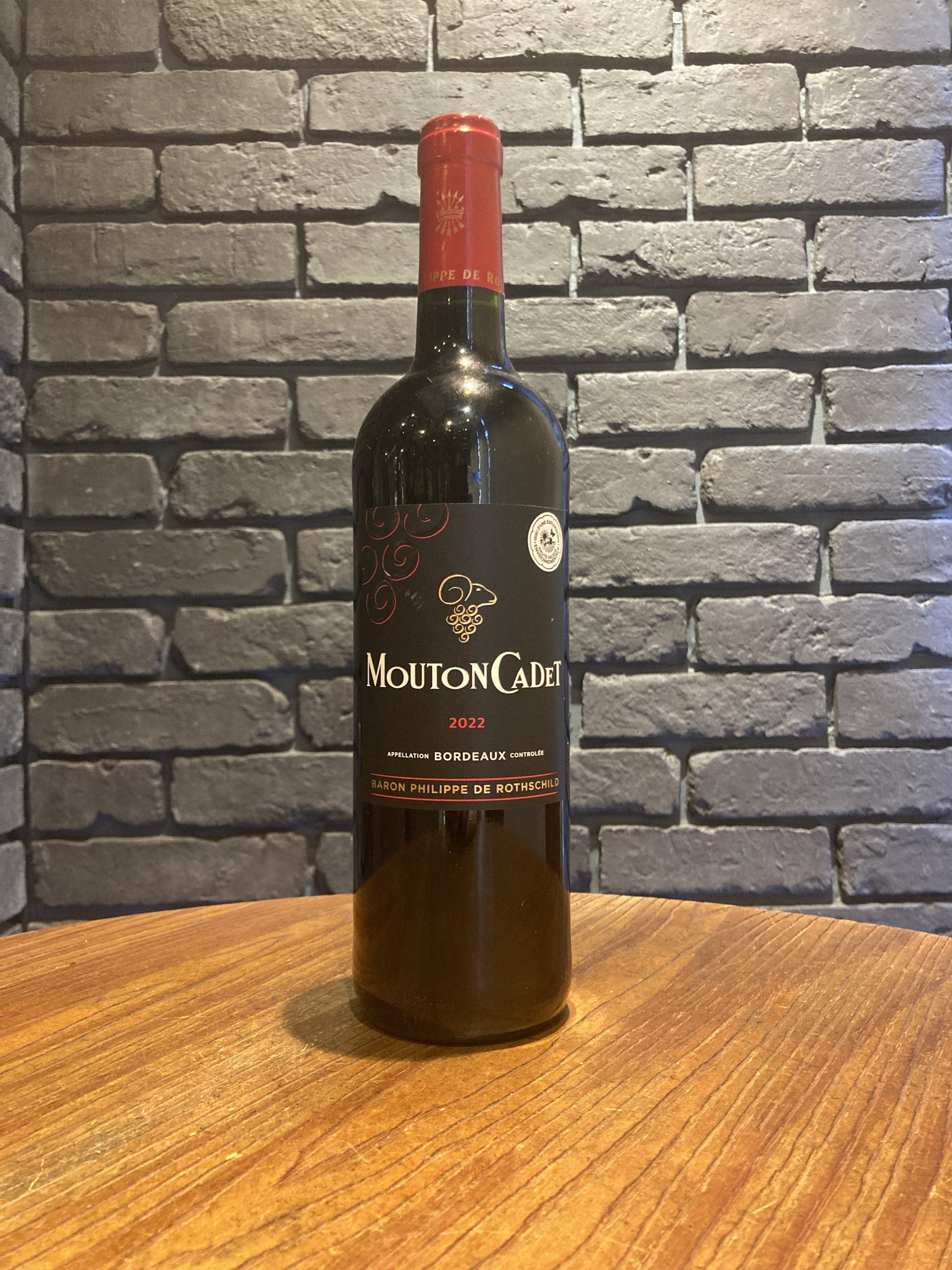 フランス産赤ワインボトル。ラベルには'MOUTON CADET'と書かれ、2022年のボルドー産と記載されている。