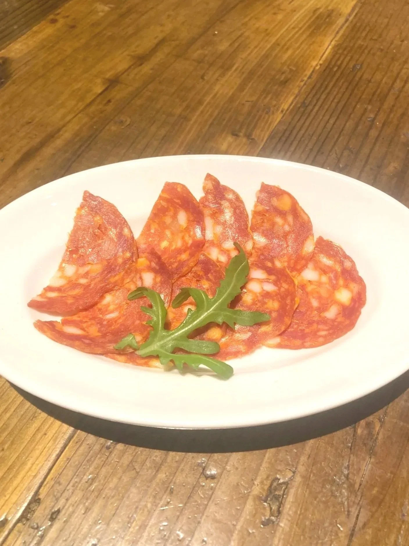 サラミのスライスにパセリの葉が添えられた白い皿