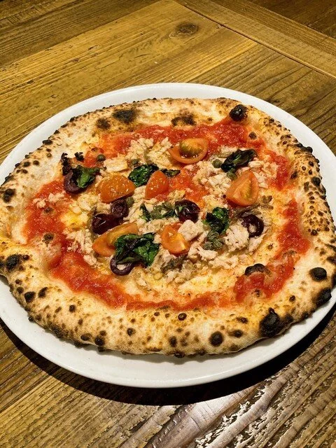 焼きたてのピザ、トマトソース、チーズ、チェリートマト、バジル、黒 olives, 鶏肉がのっている