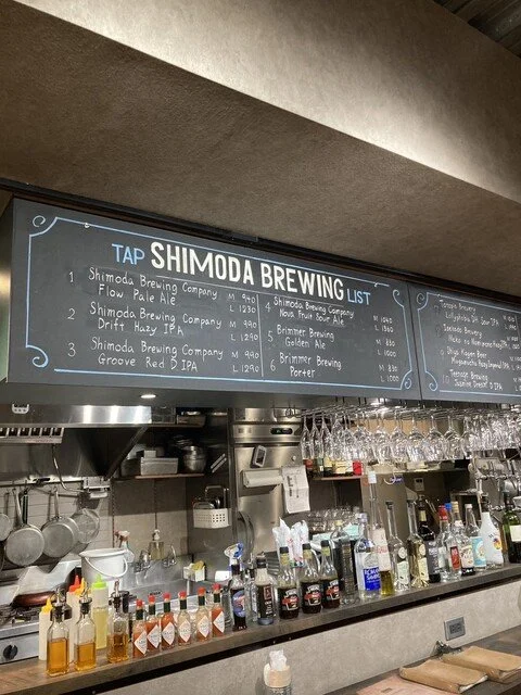 醸造所のカウンターとメニュー黒板に『SHIMODA BREWING』と書かれている。