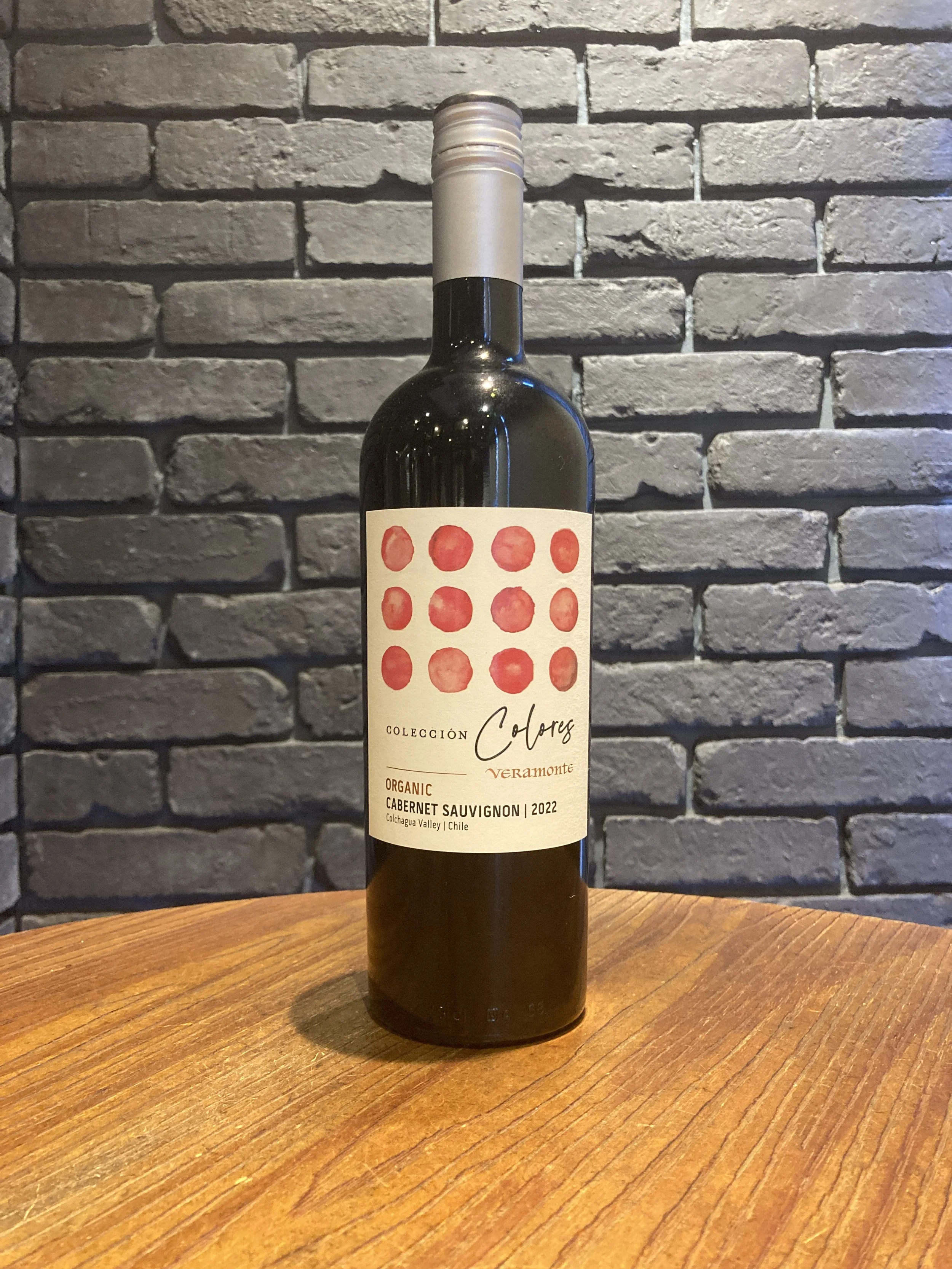 ワインのボトルが木のテーブルの上に置かれ、背景は灰色のレンガ壁。
