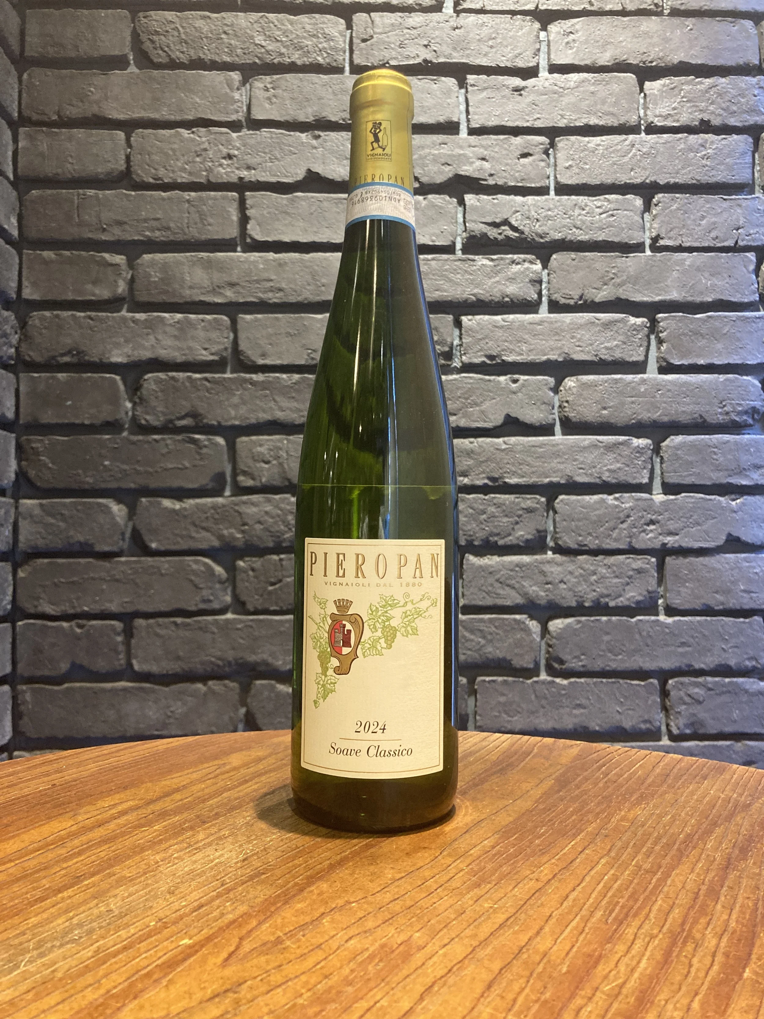 緑色のワインボトルが木製のテーブルに置かれ、背面にレンガの壁がある。