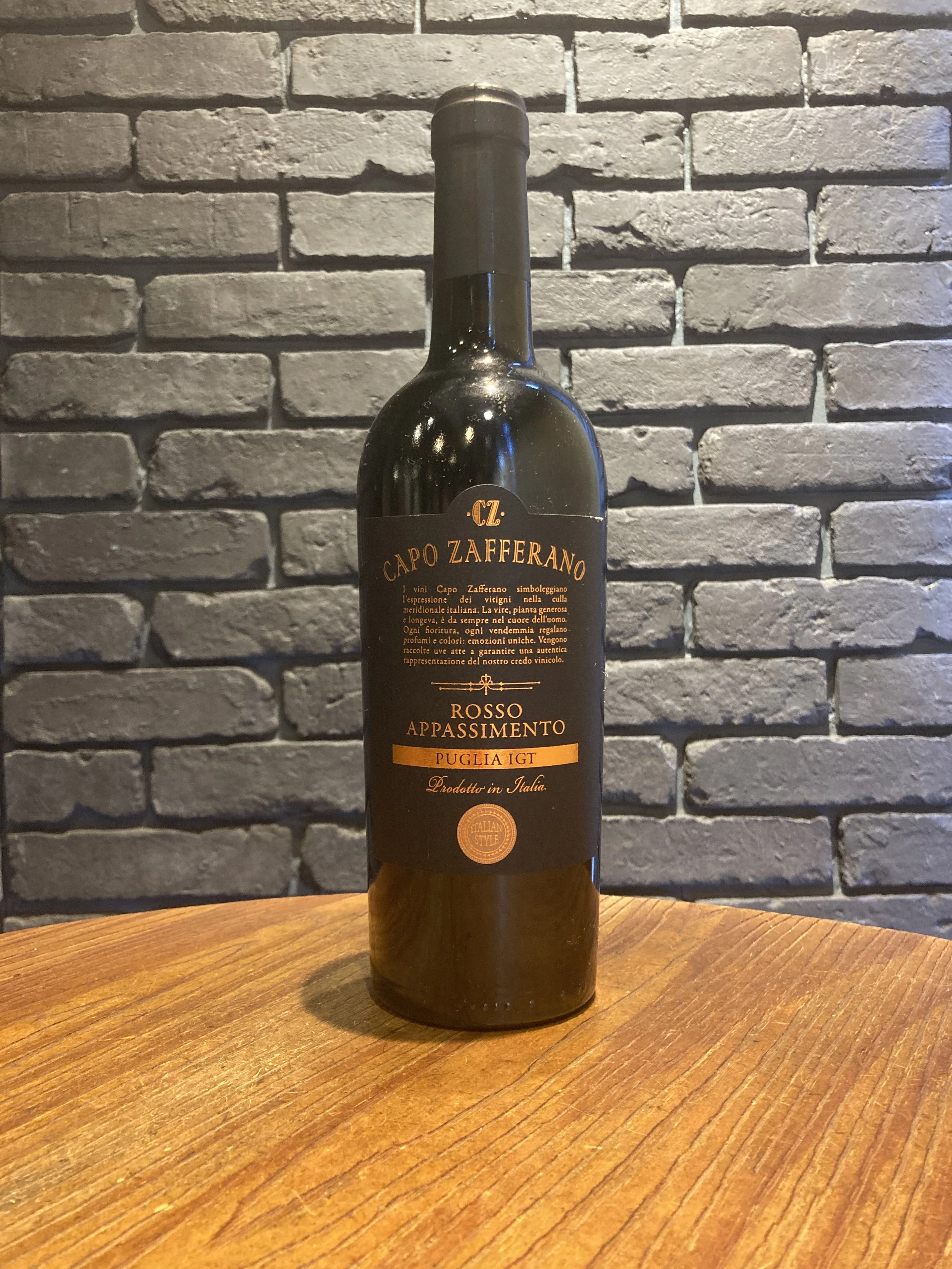 黒い瓶のワインが木のテーブルの上に置かれ、背景は灰色のレンガの壁です。