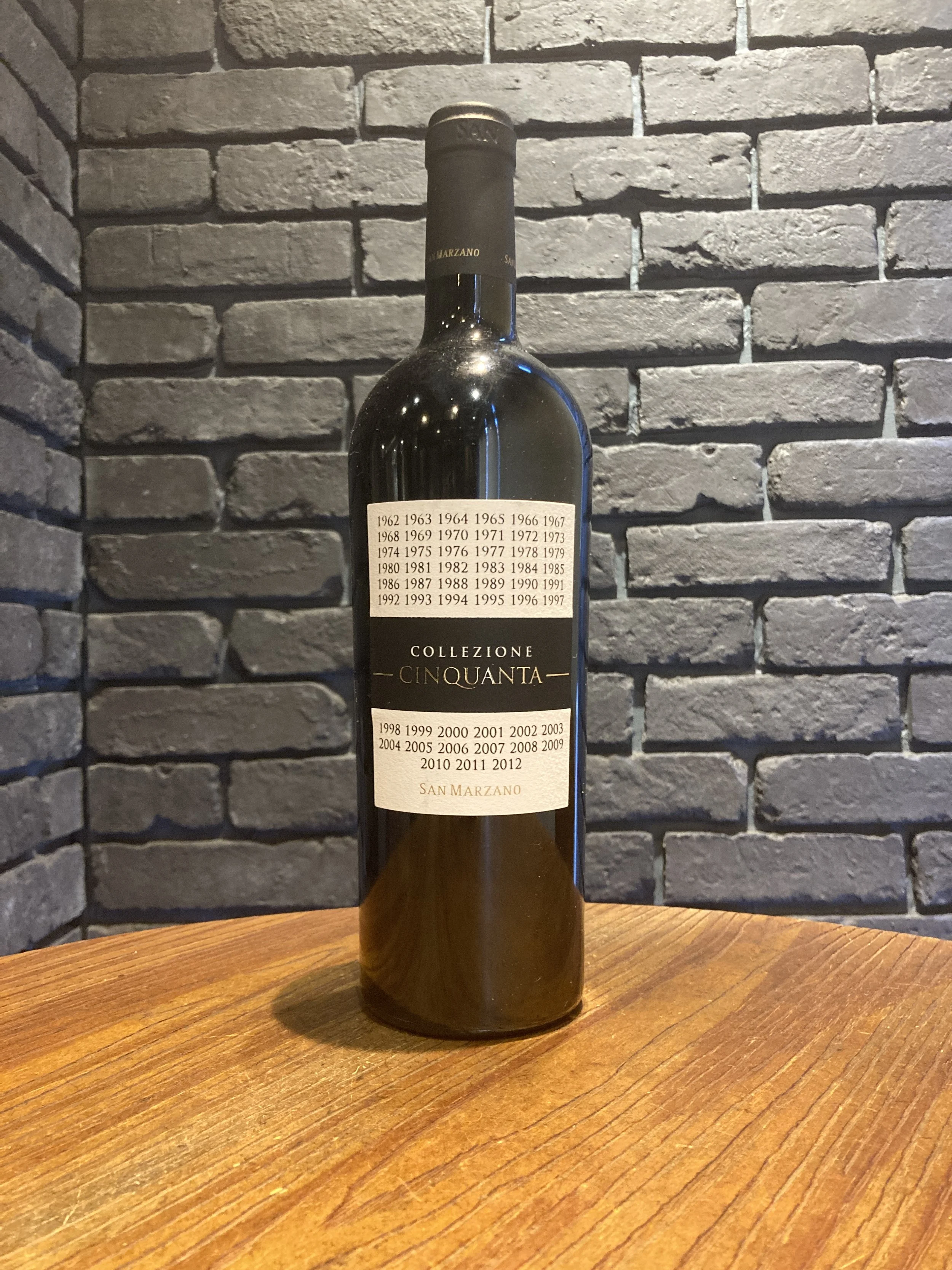 黒いラベルのワインボトル、背景はレンガの壁、木製のテーブルの上に置かれている