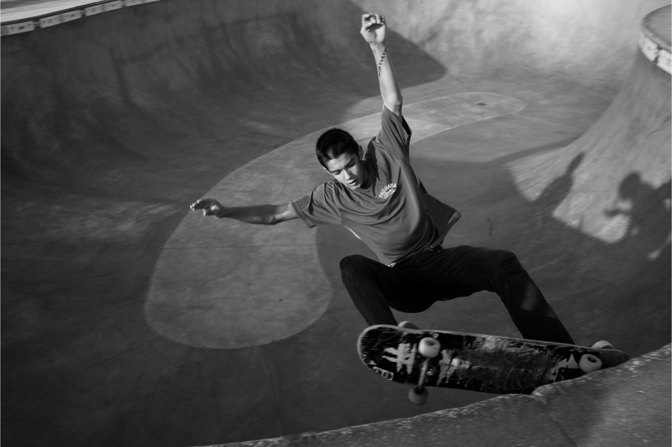 A young male skateboarder is performing a trick in a skate park bowl.