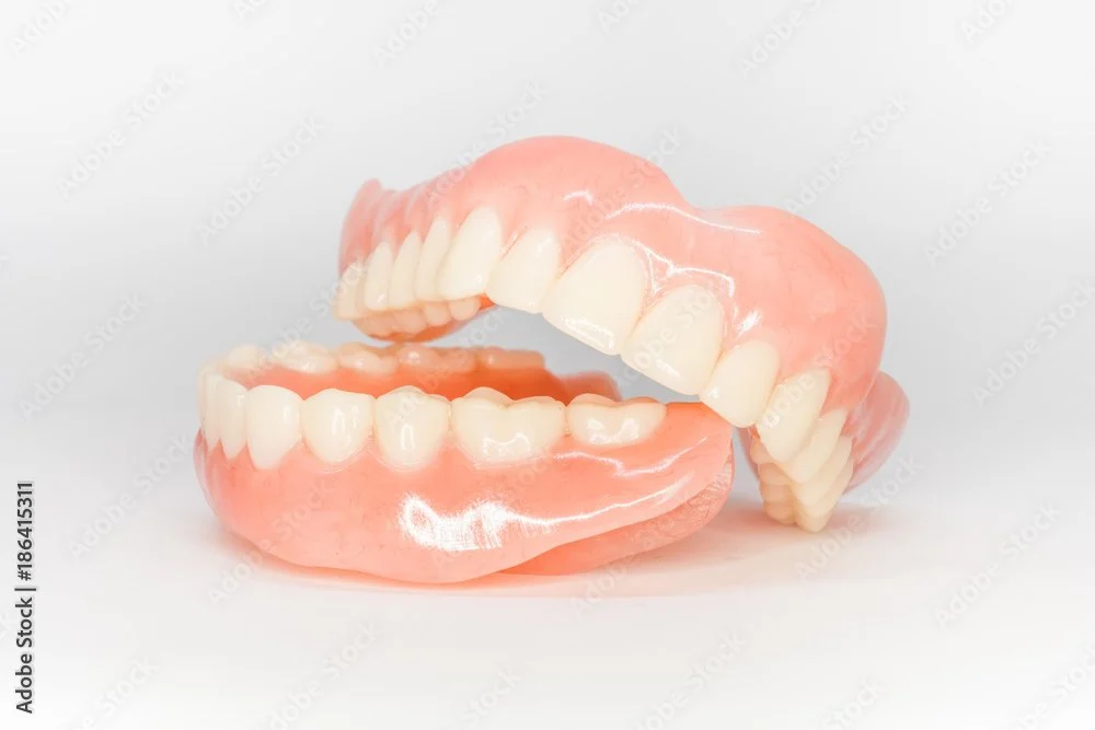 Artificial upper and lower dentures displayed against a white background.
