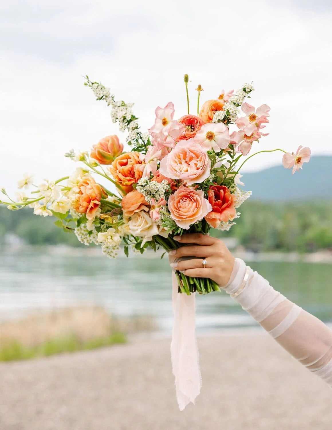 Bride and groom sharing a kiss under a wedding veil outside a church, with the bride holding a bouquet of flowers.