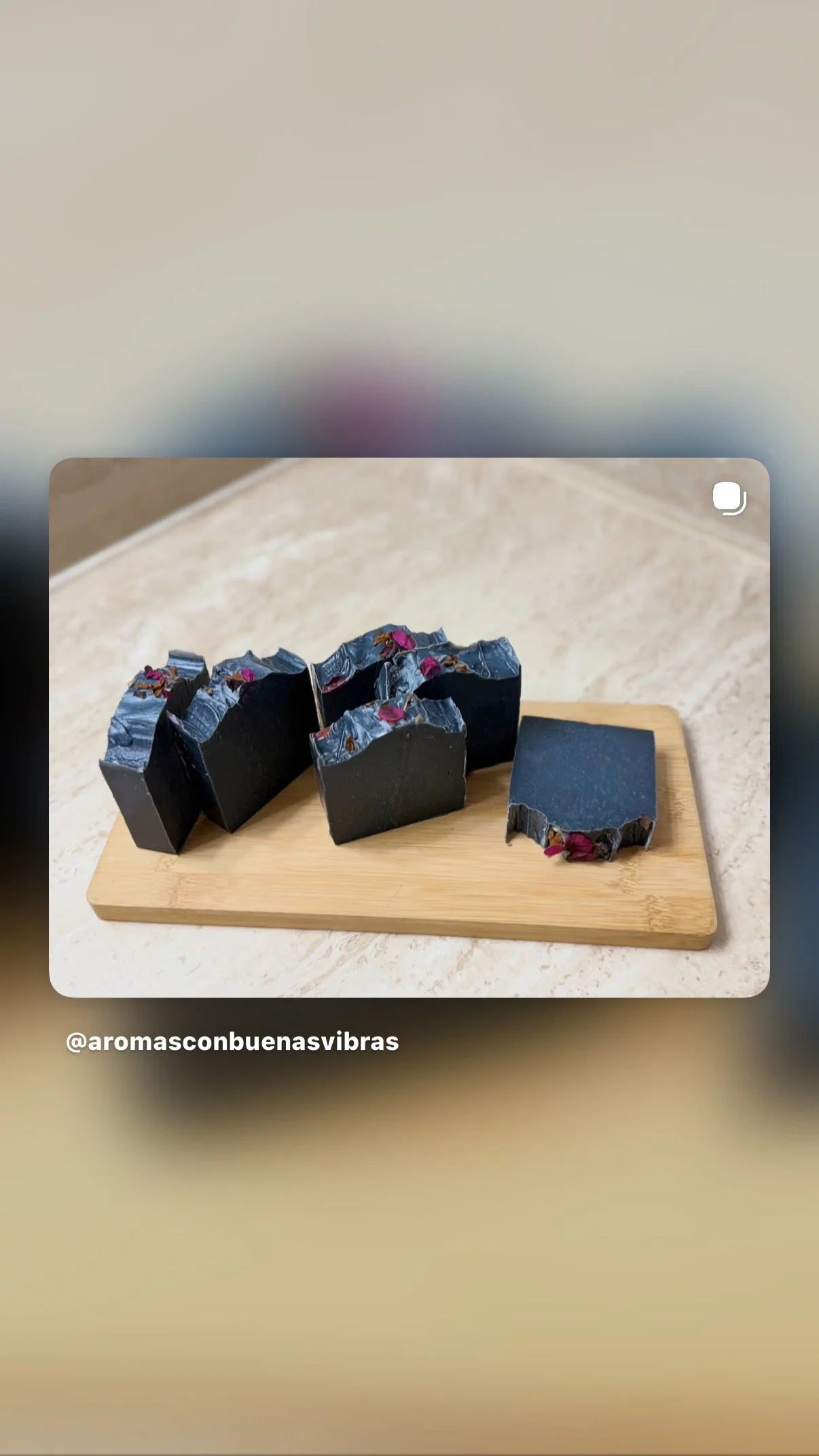 Jabones negros con pétalos de rosa en una tabla de madera.