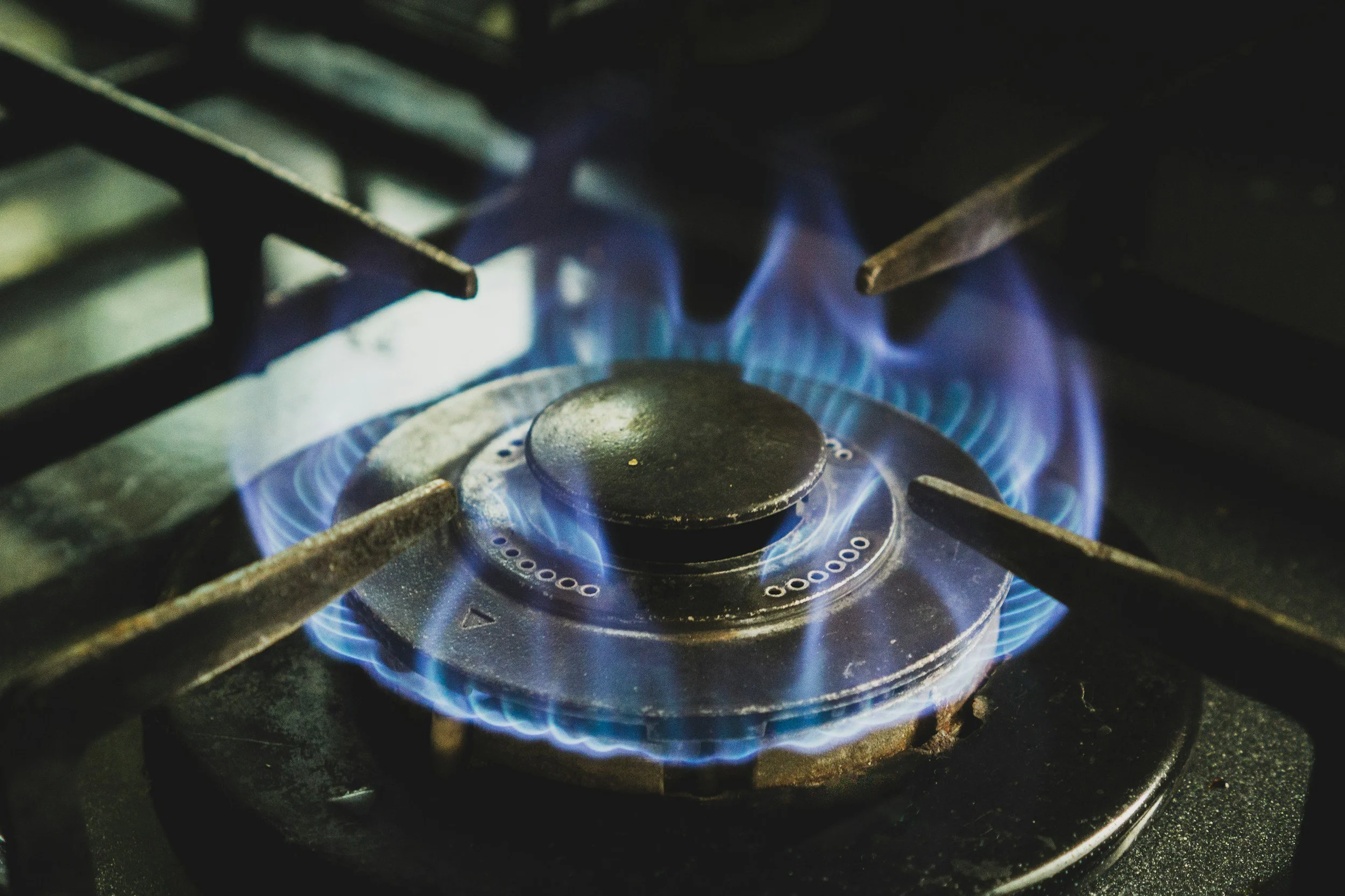 Close-up of a lit gas stove burner with blue flames.