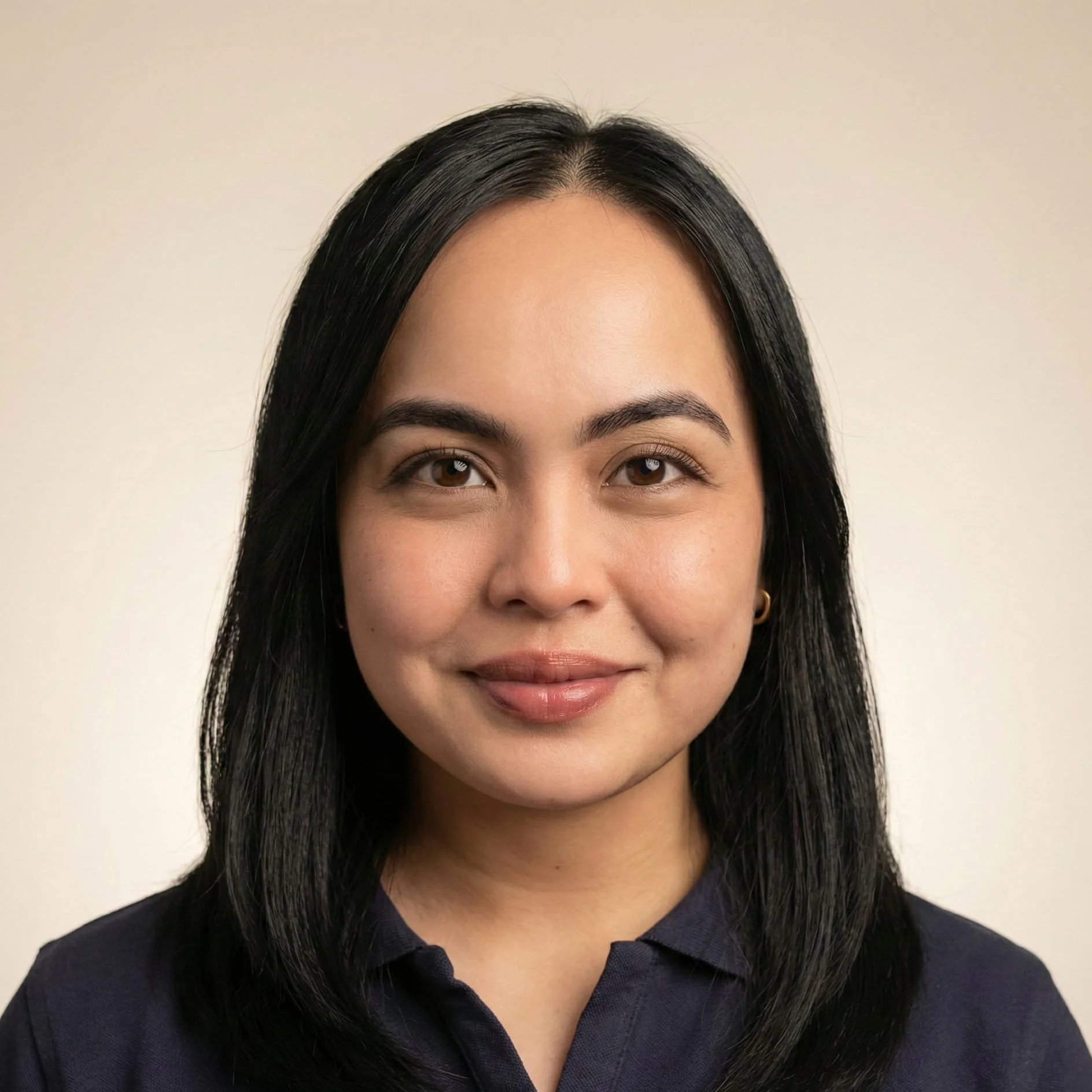 Close-up portrait of a smiling woman with black hair, brown eyes, wearing a dark shirt, against a light background.