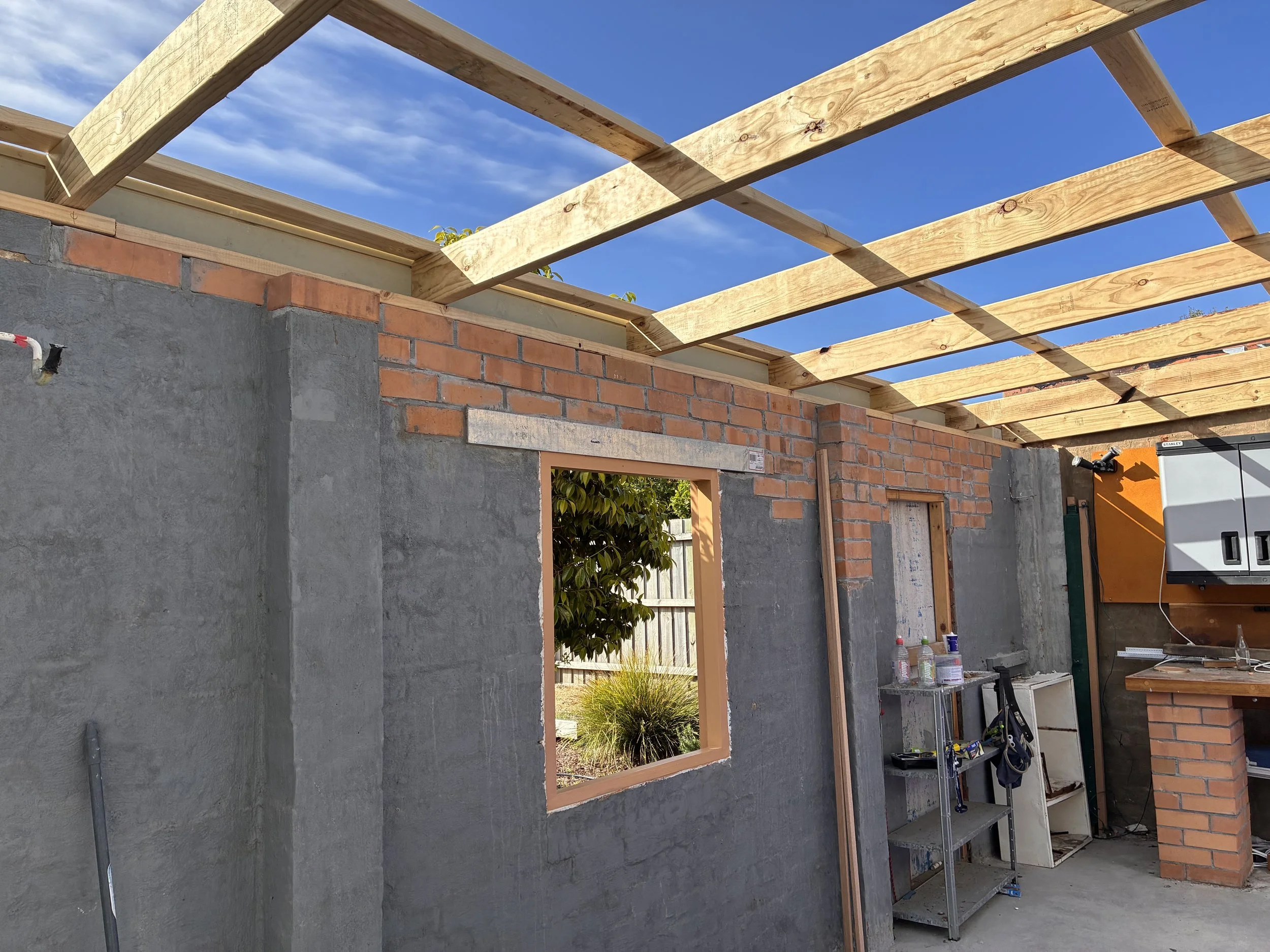 Rebuilt structural brick wall with new window and door lintels and newly constructed timber roof framing during a Melbourne Garage renovation project.