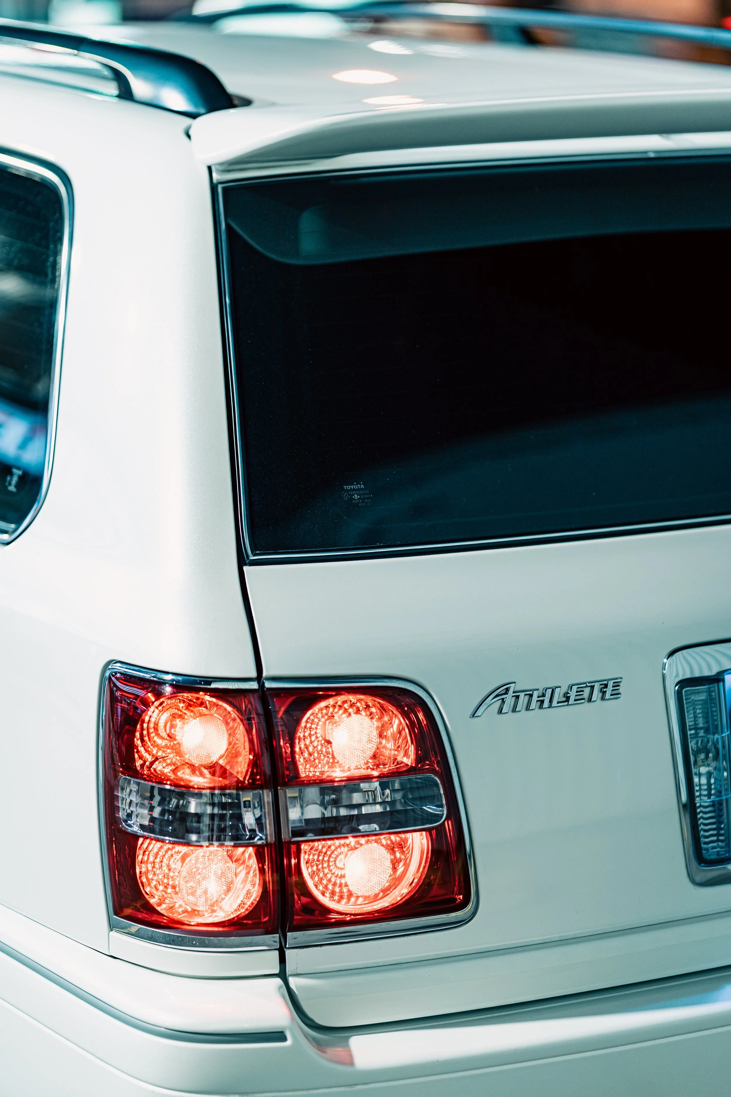 Close-up of the rear corner of a white Toyota Athlete SUV, showing the tail light and the 'Athlete' badge.